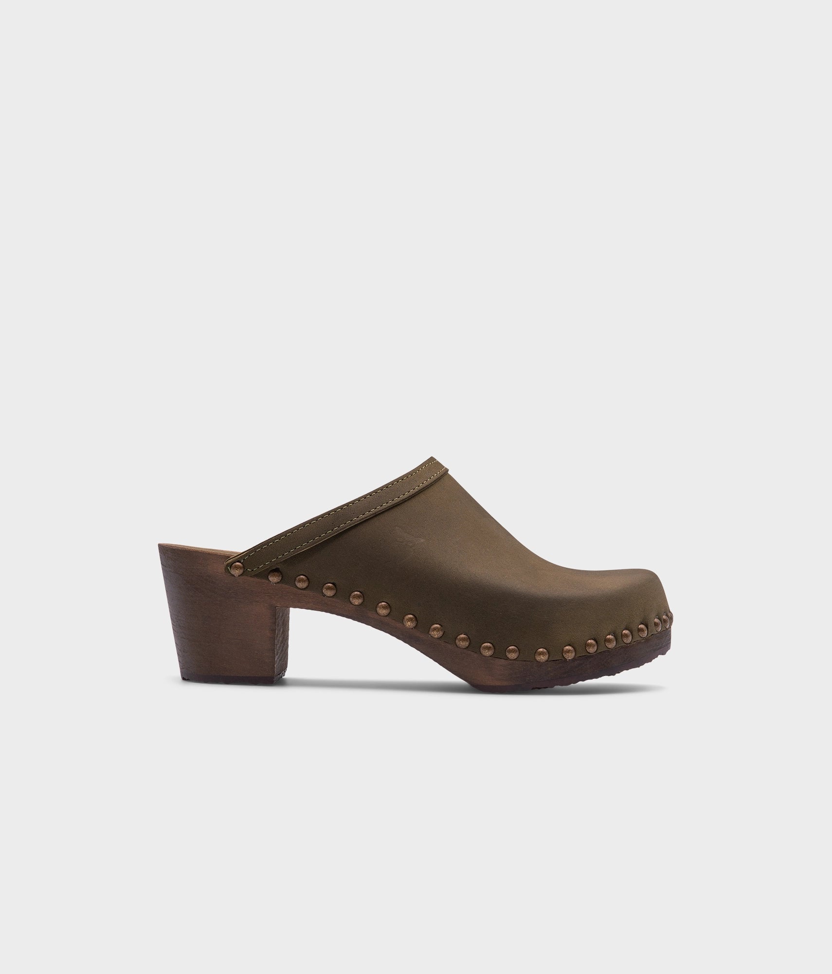 high heeled clog mules in olive green nubuck leather stapled on a dark wooden base with brass gold studs