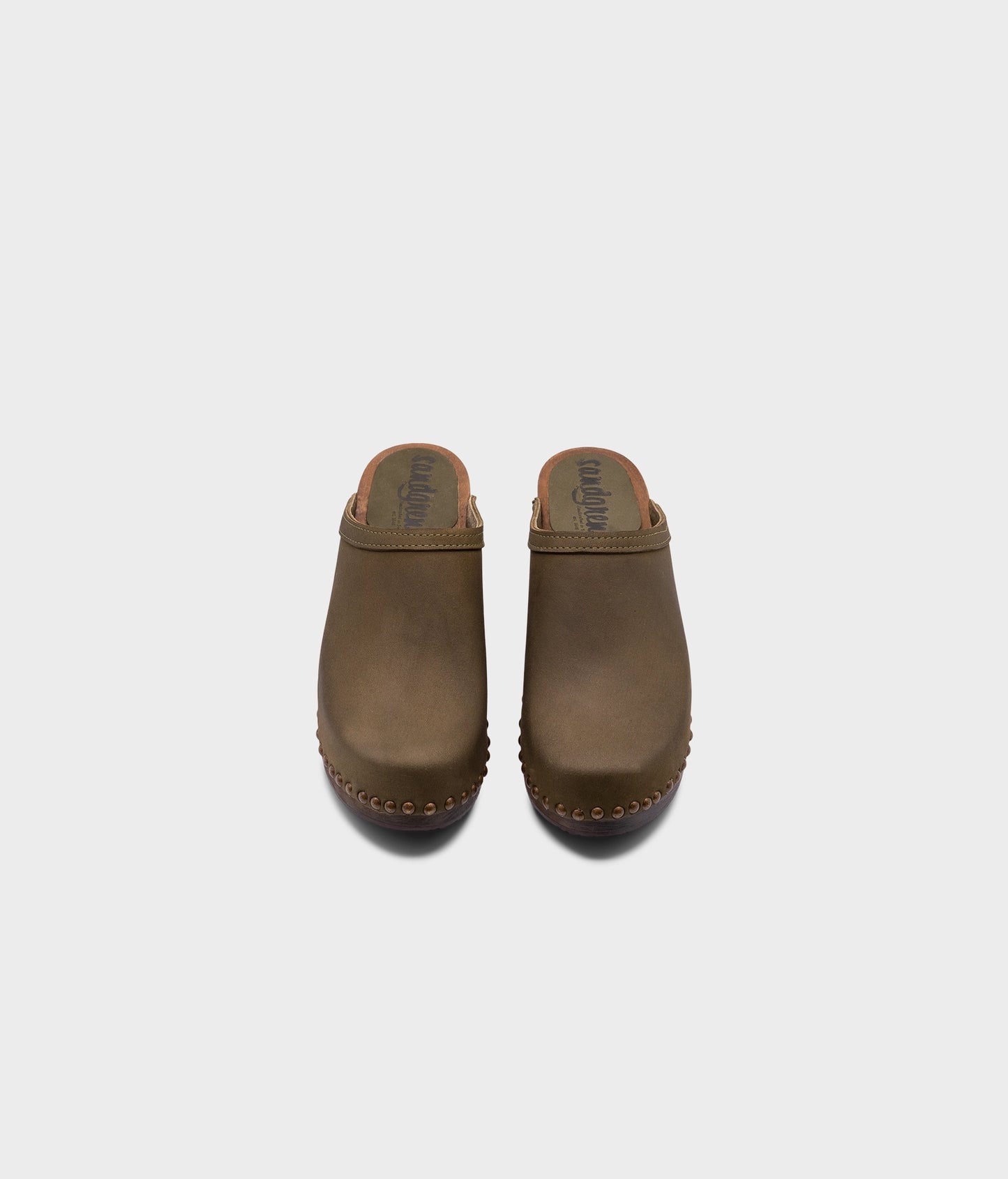 high heeled clog mules in olive green nubuck leather stapled on a dark wooden base with brass gold studs