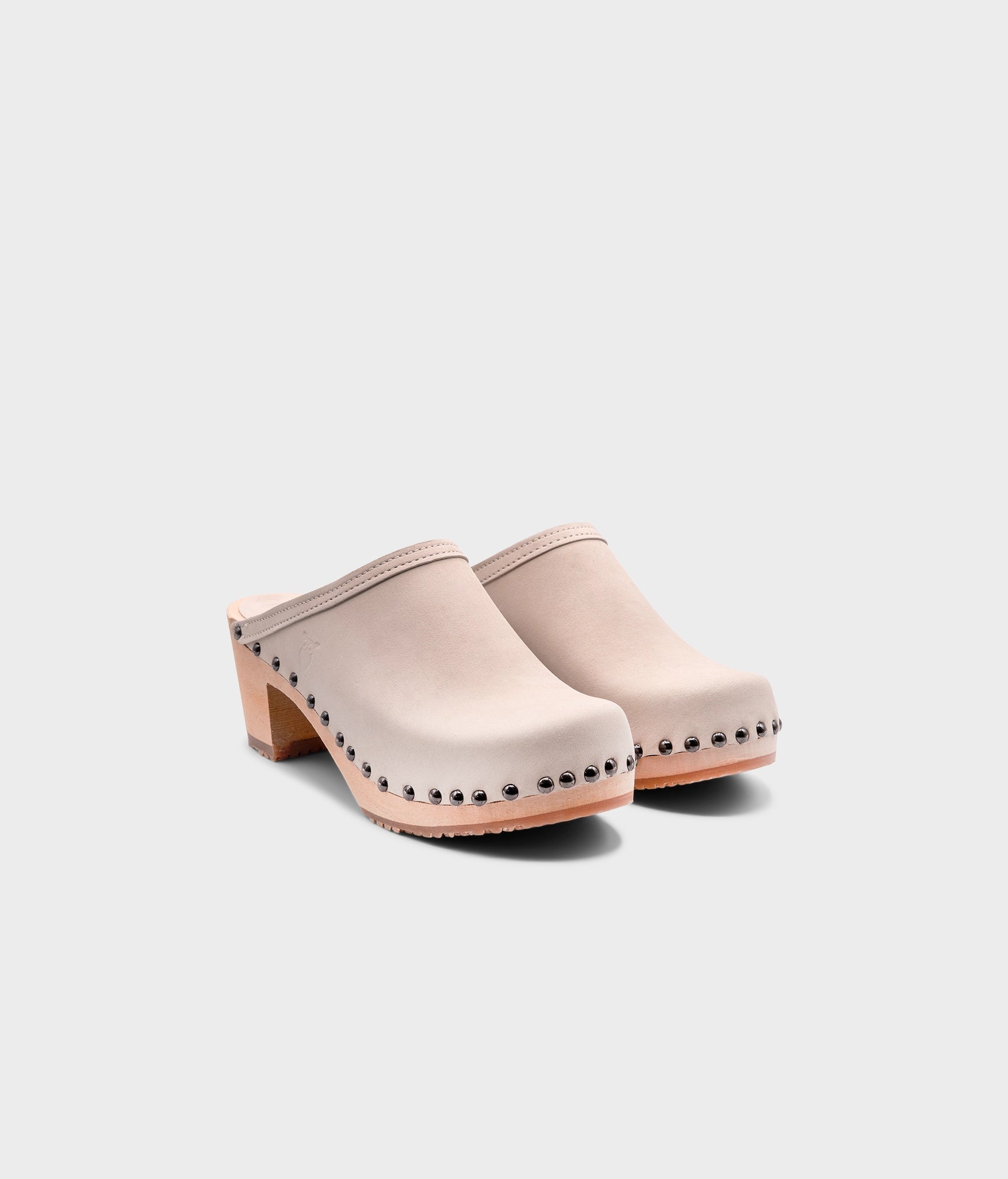 high heeled clog mules in sand white nubuck leather stapled on a light wooden base with dark silver studs