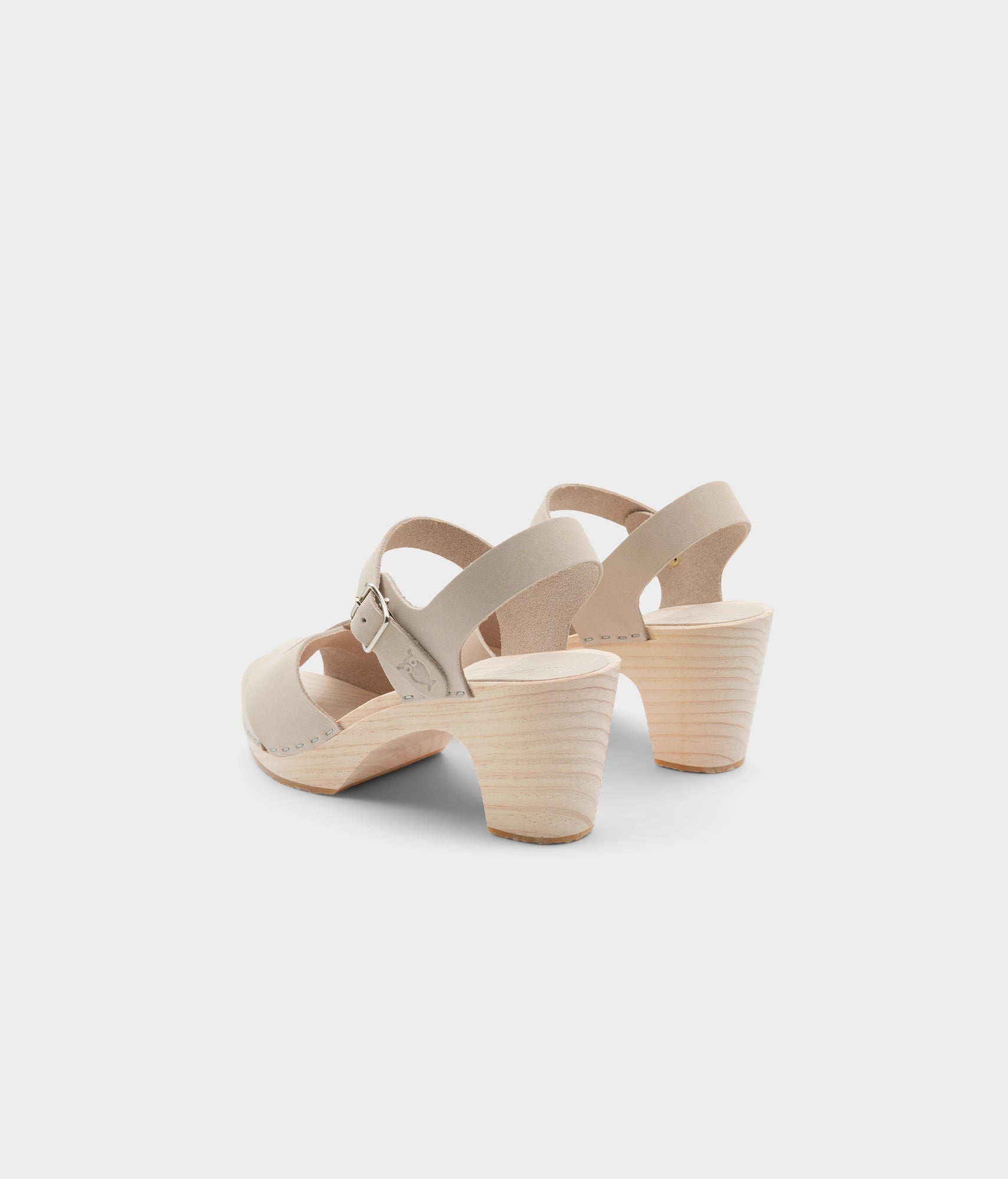 high rise heel crossed clog sandals in white sand nubuck leather stapled on a light wooden base
