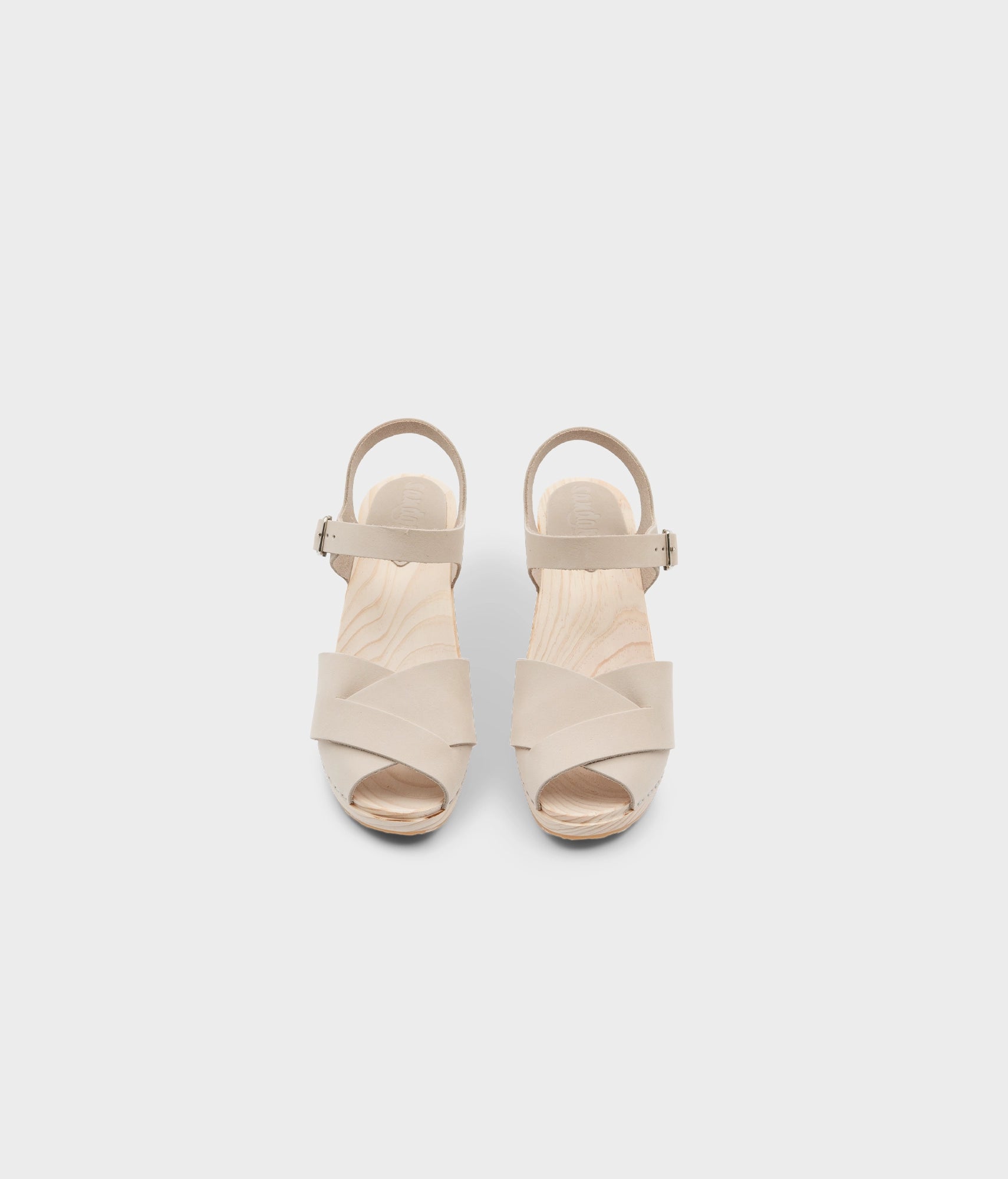 high rise heel crossed clog sandals in white sand nubuck leather stapled on a light wooden base