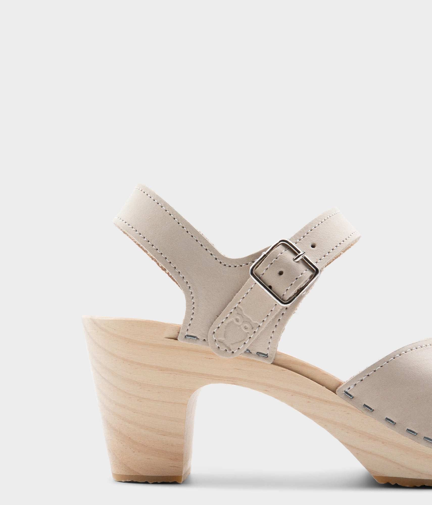 high rise heel crossed clog sandals in white sand nubuck leather stapled on a light wooden base