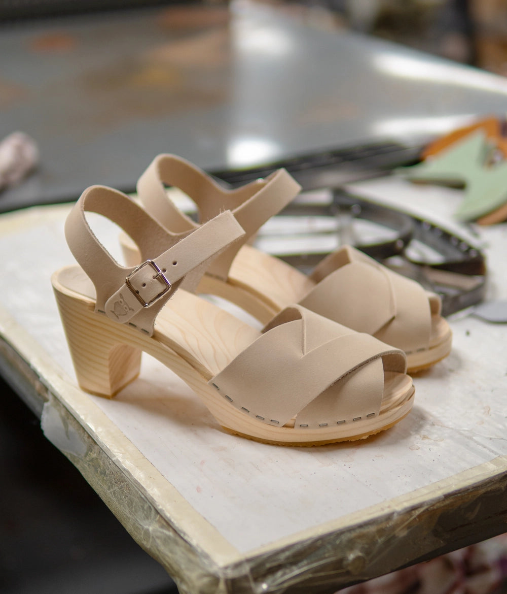 high rise heel crossed clog sandals in white sand nubuck leather stapled on a light wooden base