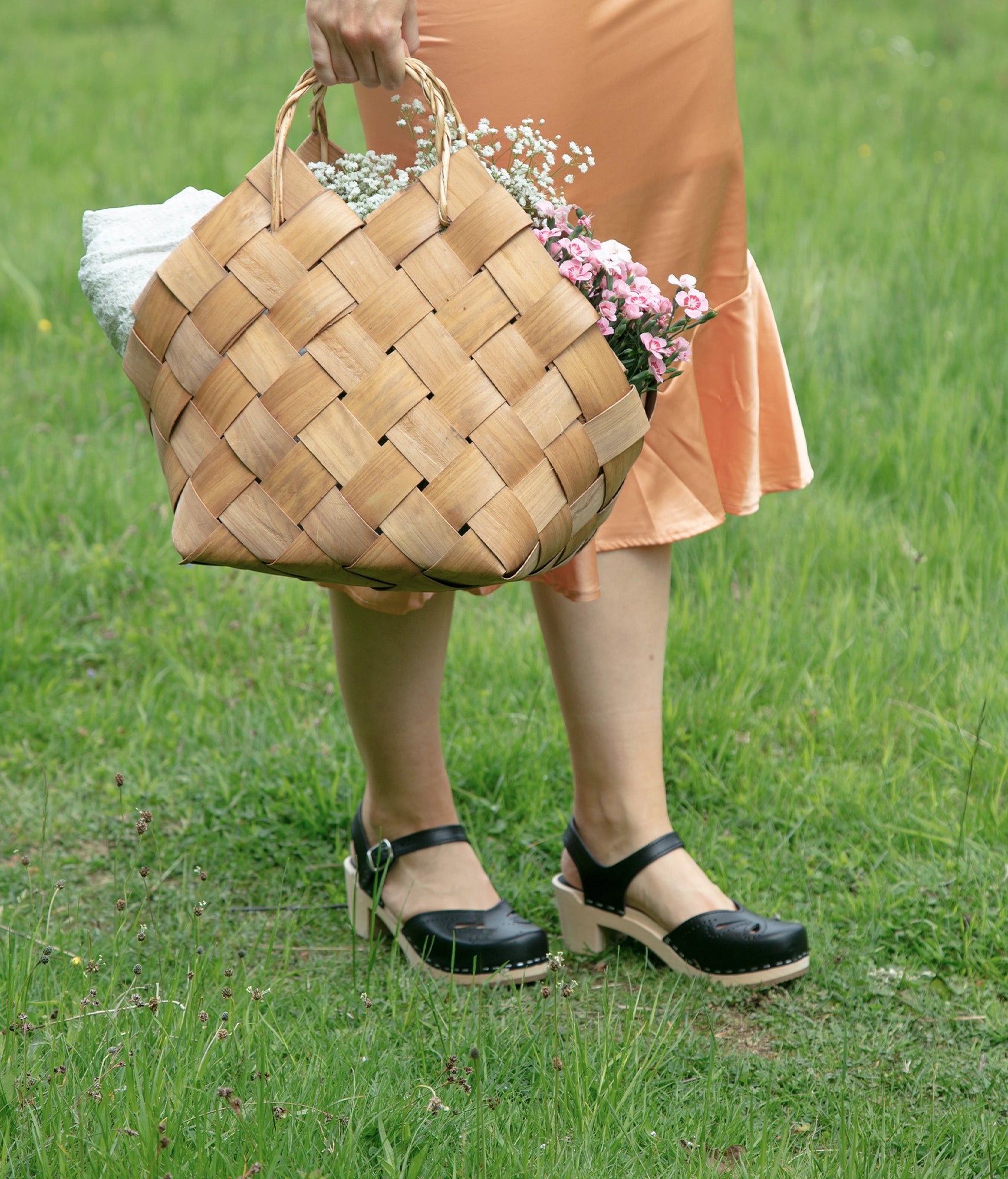 high-heeled clog sandal in black vegetable tanned leather with a blossom cut-out over the toe stapled on a light wooden base