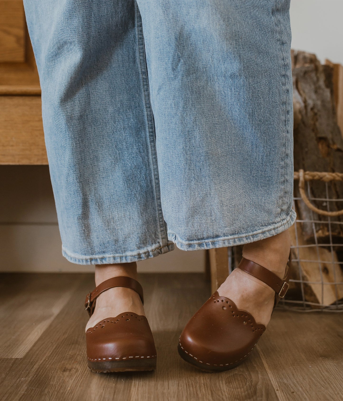 low heeled closed-toe clog sandals in cognac red vegetable tanned leather with a wavy leather cutout stapled on a dark wooden base
