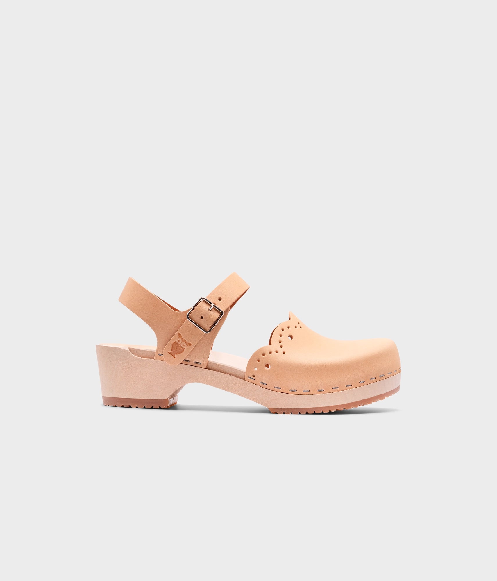 low heeled closed-toe clog sandals in ecru beige vegetable tanned leather with a wavy leather cutout stapled on a light wooden base