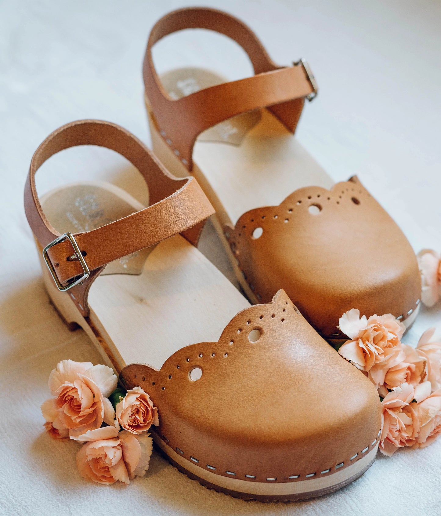 low heeled closed-toe clog sandals in ecru beige vegetable tanned leather with a wavy leather cutout stapled on a light wooden base