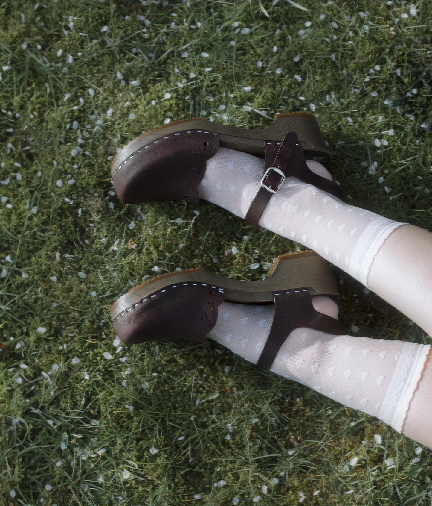 low heeled closed-toe clog sandals in plum purple nubuck leather with a wavy leather cutout stapled on a dark wooden base