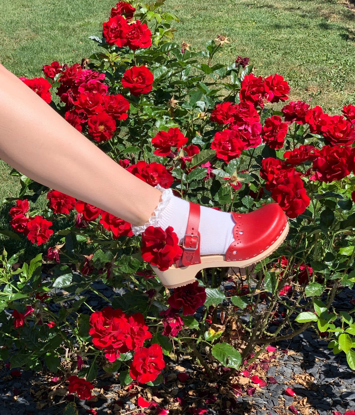 low heeled closed-toe clog sandals in red vegetable tanned leather with a wavy leather cutout stapled on a light wooden base