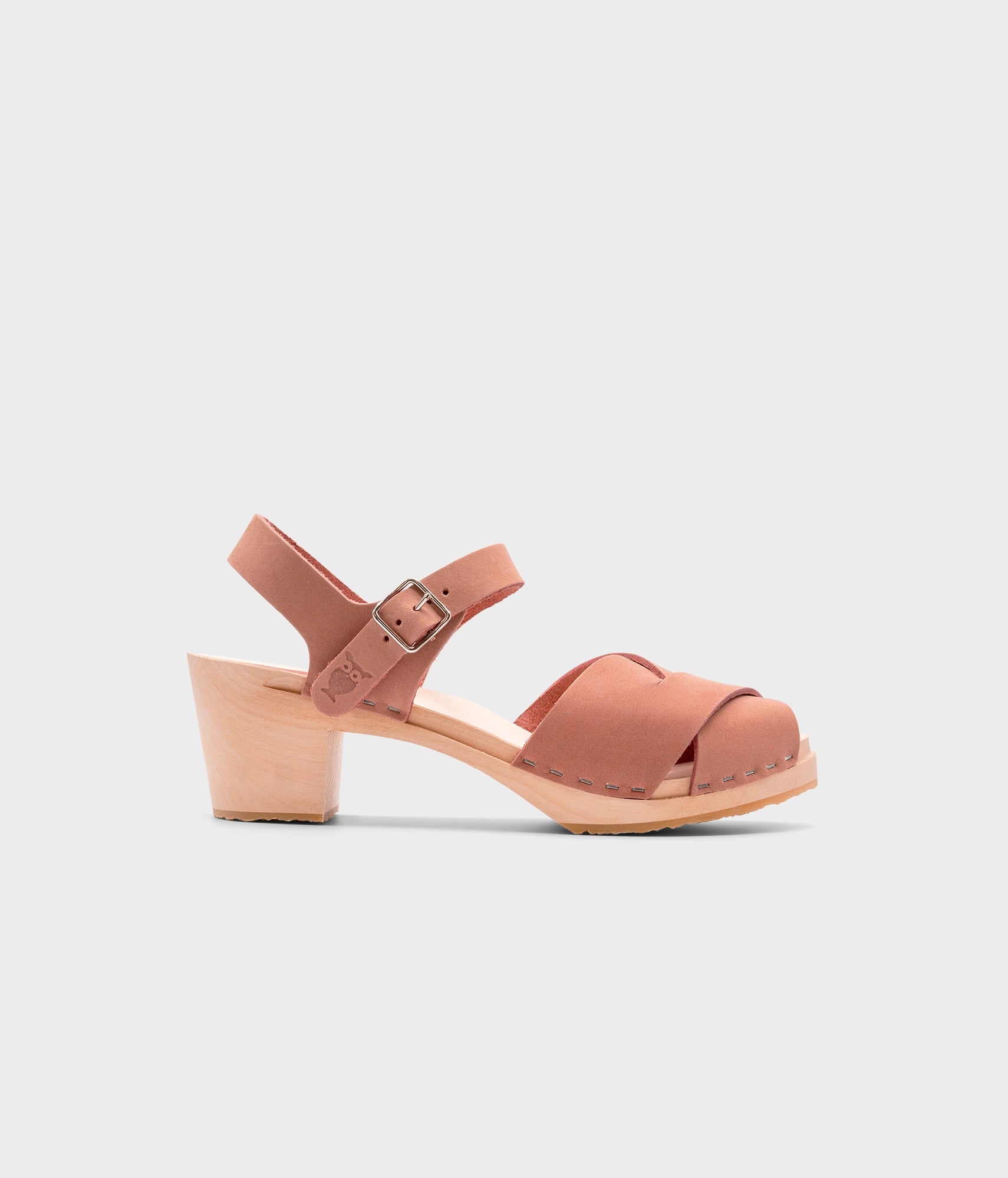 high heeled clog sandals in blush pink nubuck leather with an open-toe stapled on a light wooden base