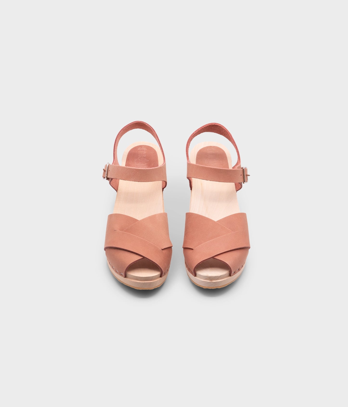 high heeled clog sandals in blush pink nubuck leather with an open-toe stapled on a light wooden base