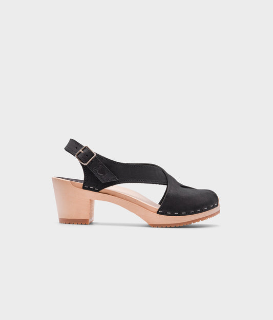 high heeled criss cross clog sandals in black nubuck leather stapled on a light wooden base