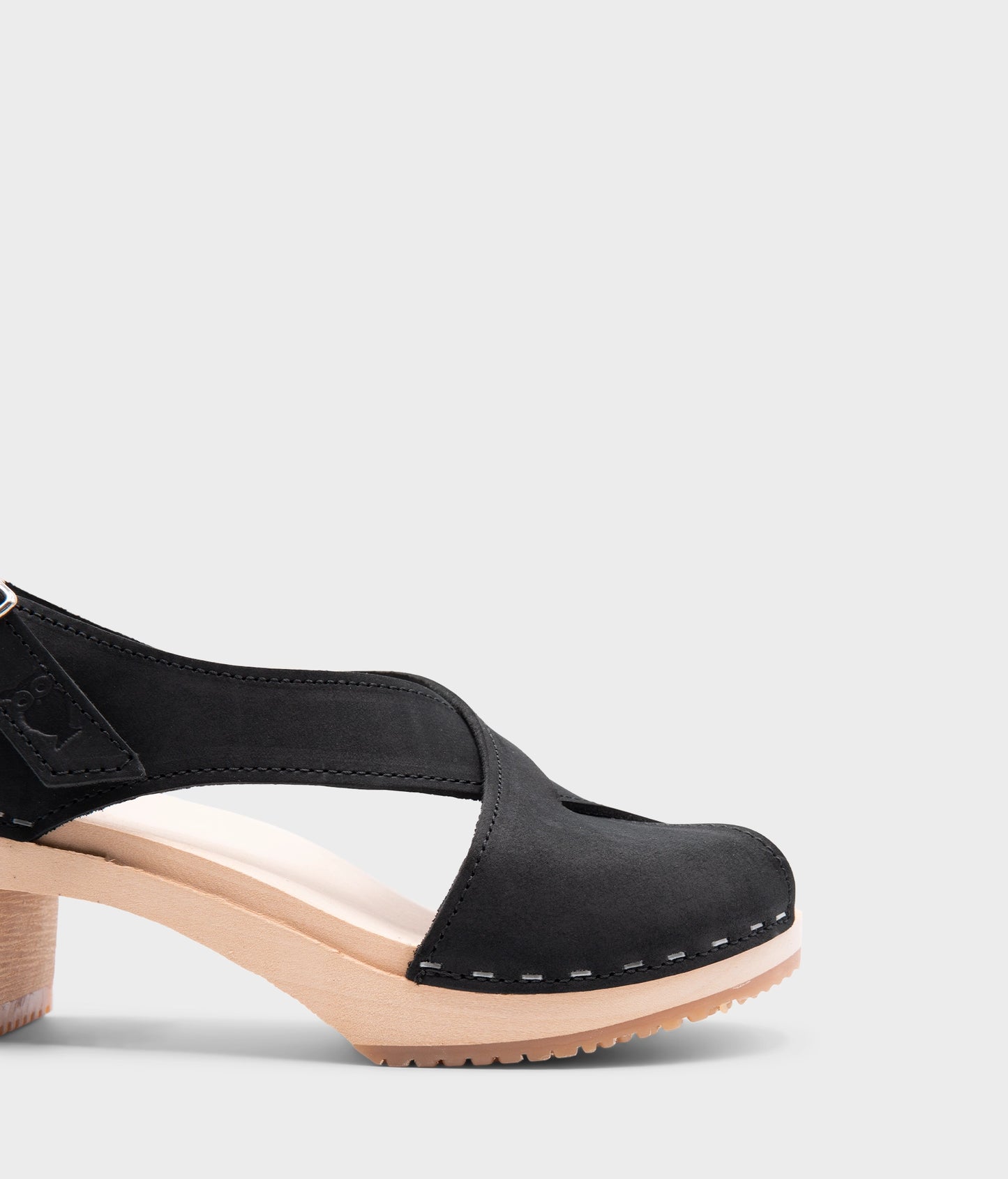 high heeled criss cross clog sandals in black nubuck leather stapled on a light wooden base