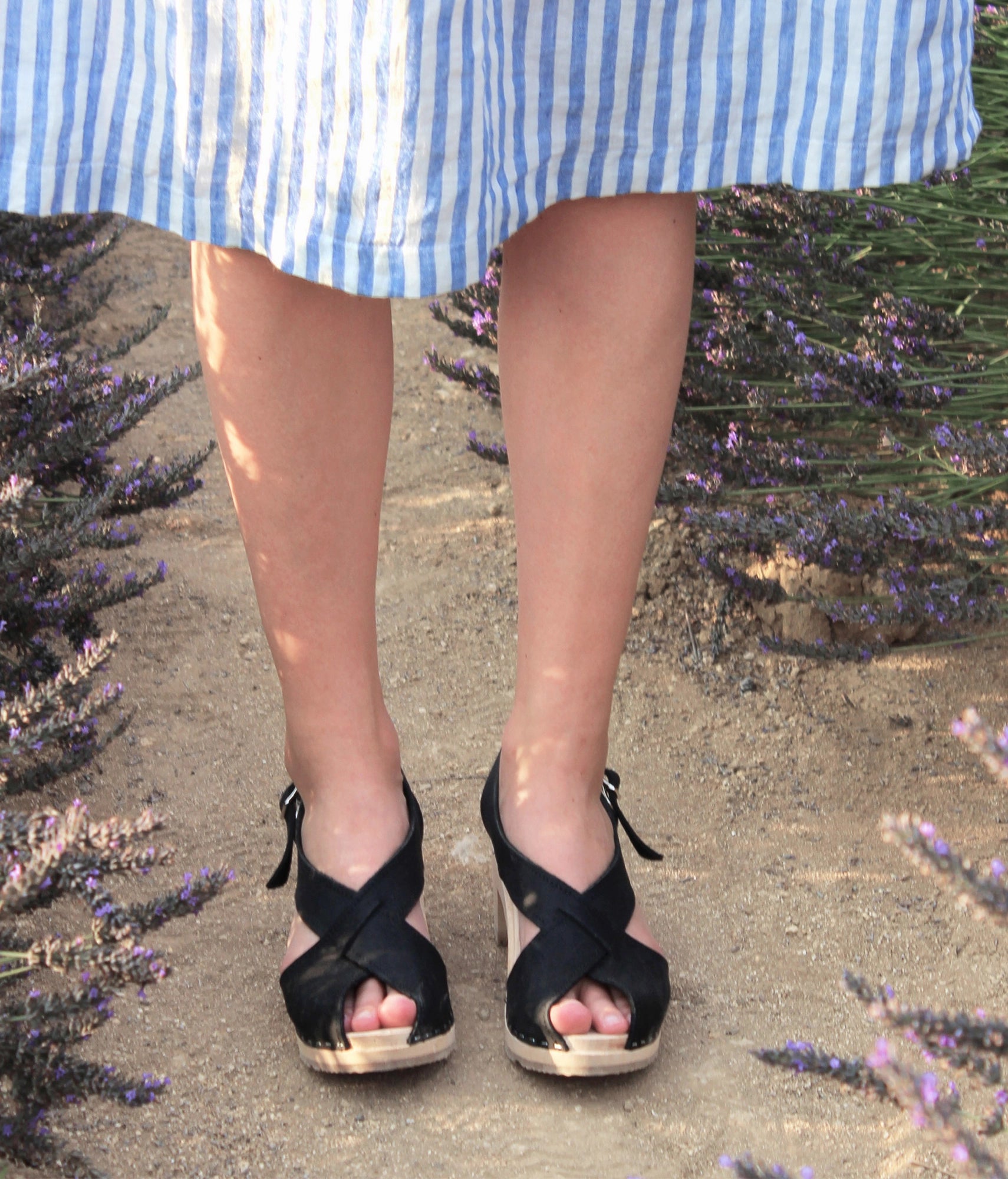 high heeled criss cross clog sandals in black nubuck leather stapled on a light wooden base