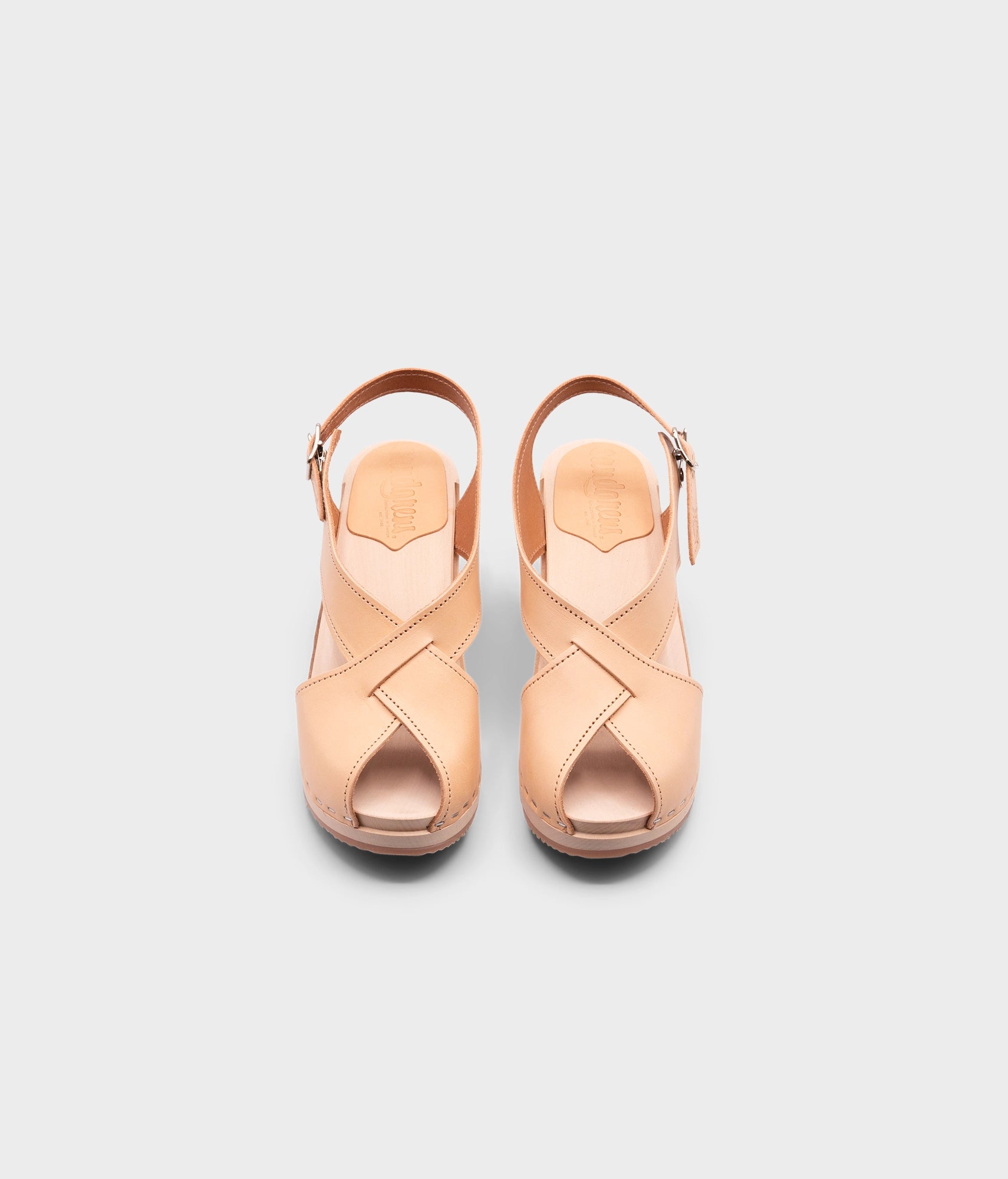 high heeled criss cross clog sandals in ecru beige vegetable tanned leather stapled on a light wooden base