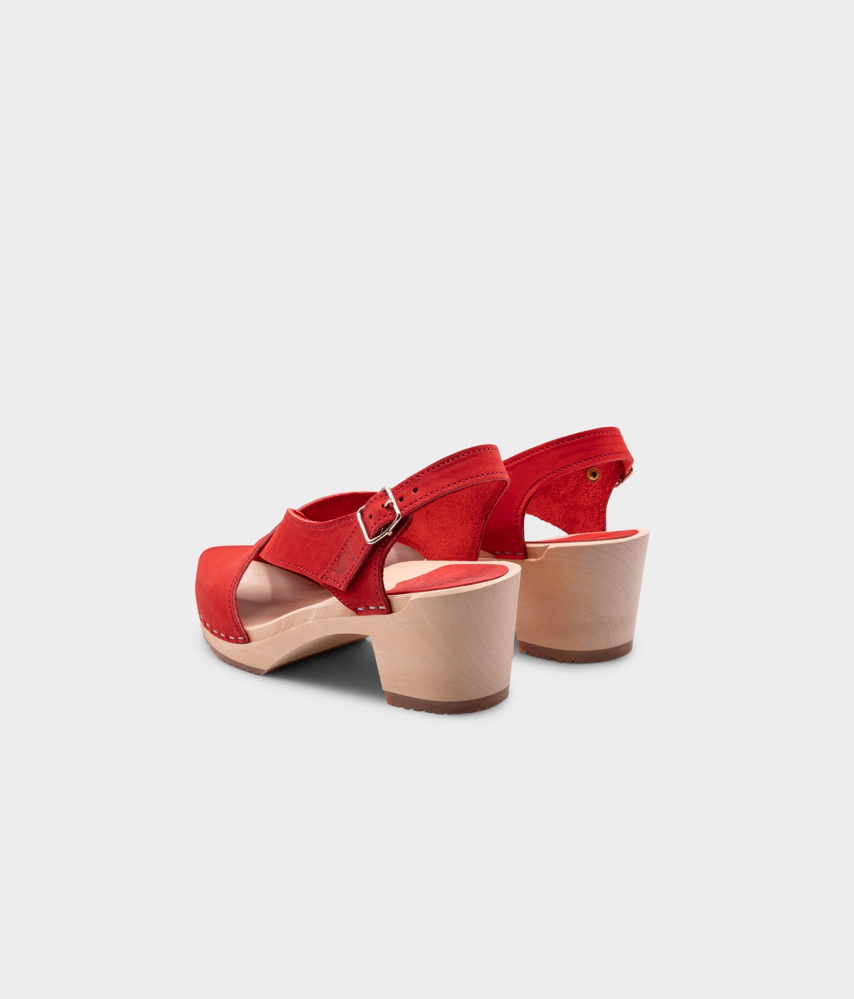 high heeled criss cross clog sandals in red nubuck leather stapled on a light wooden base
