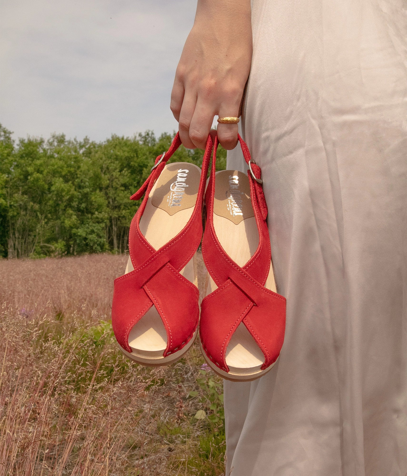 high heeled criss cross clog sandals in red nubuck leather stapled on a light wooden base