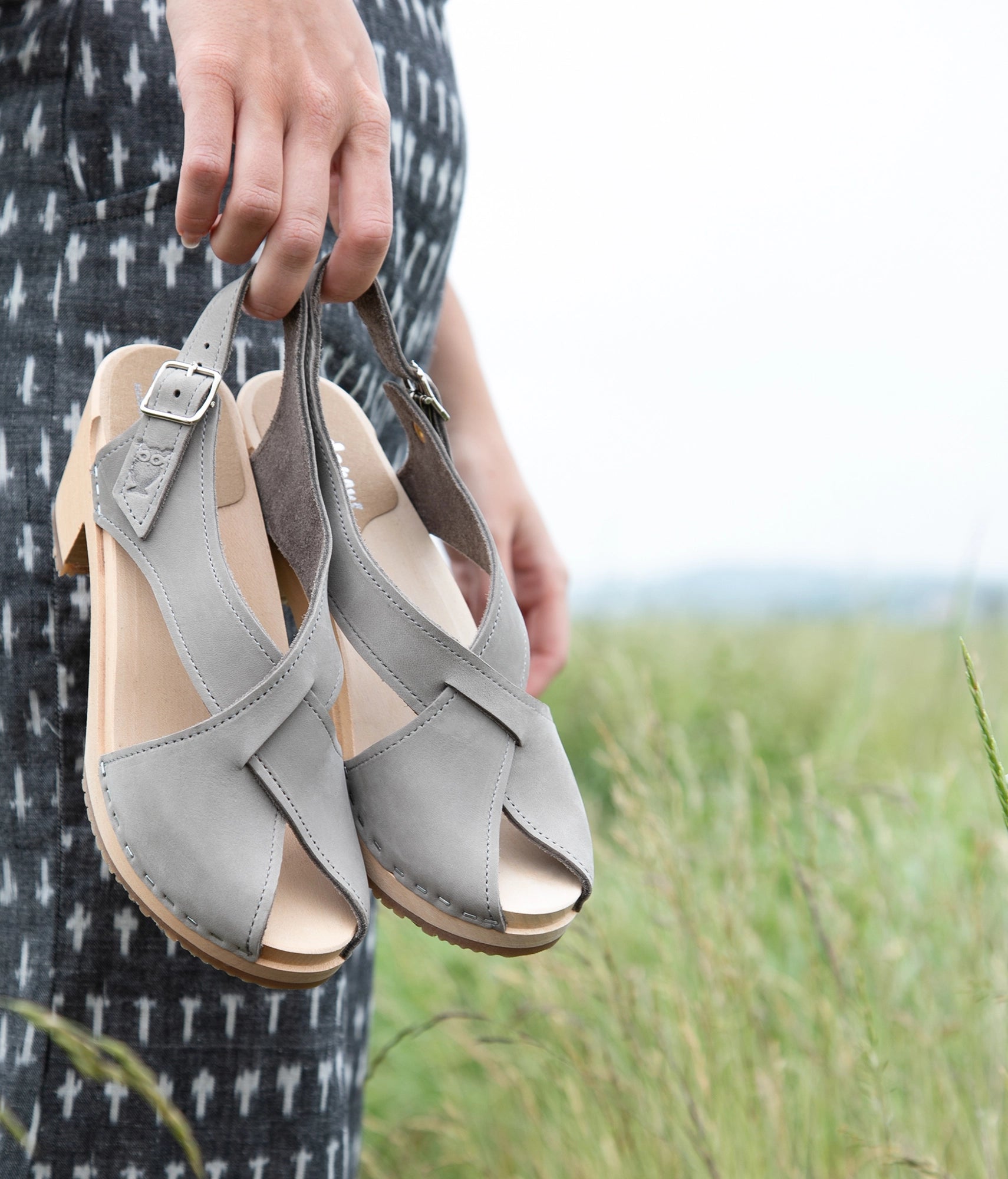 high heeled criss cross clog sandals in stone grey nubuck leather stapled on a light wooden base
