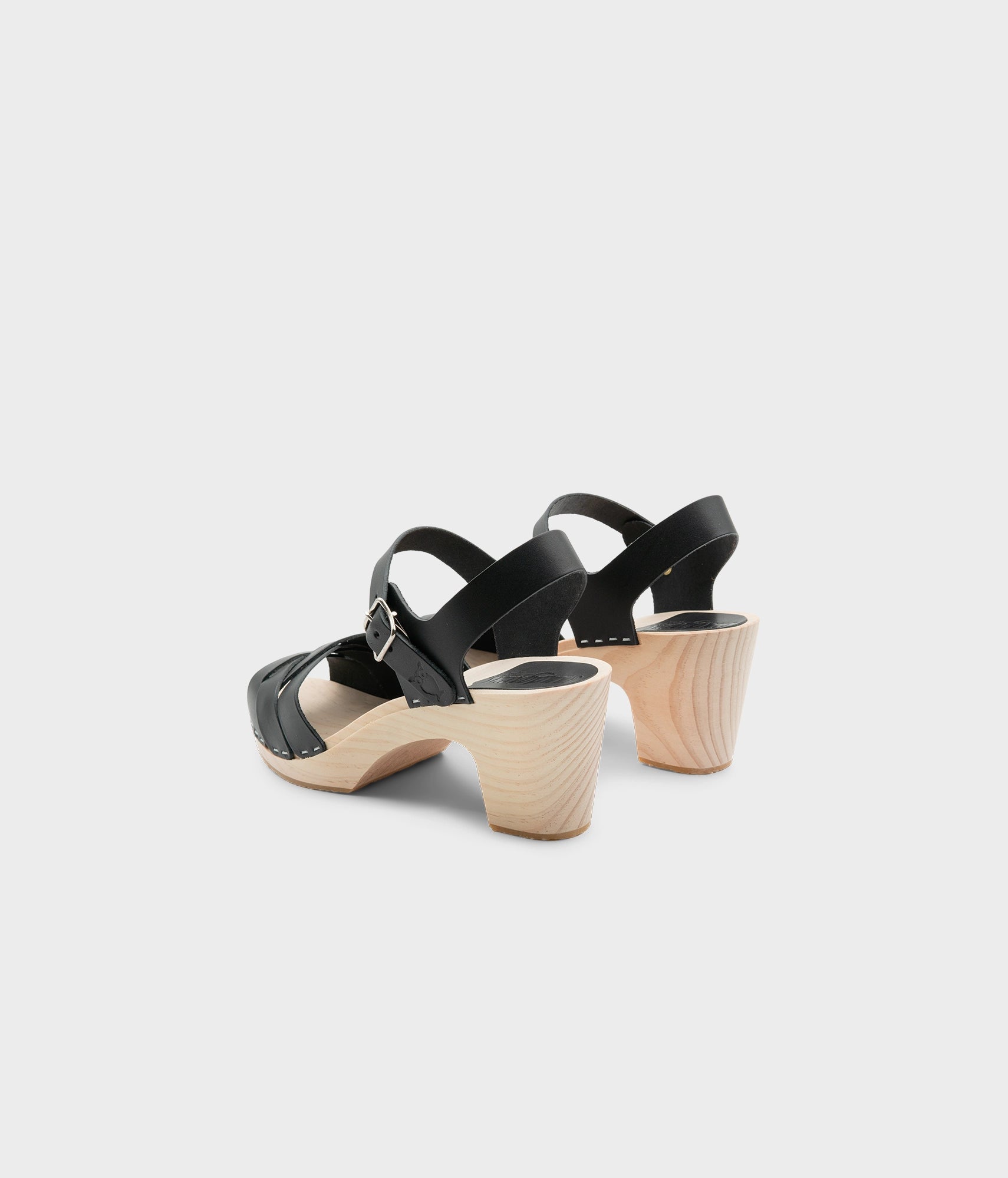 High rise heel clog sandals in black vegetable tanned leather stapled on a light wooden base with an open toe