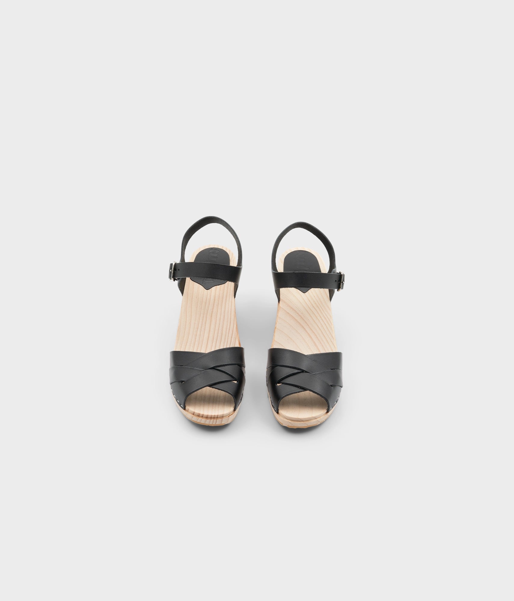 High rise heel clog sandals in black vegetable tanned leather stapled on a light wooden base with an open toe
