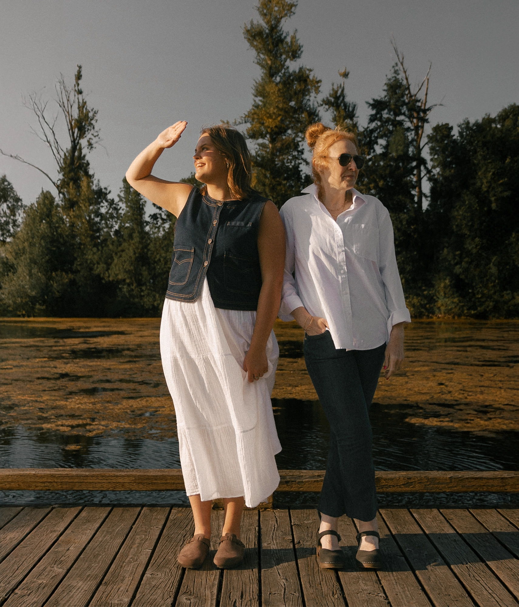 Two women standing on wooden planks in handmade wooden clogs and cork sandals