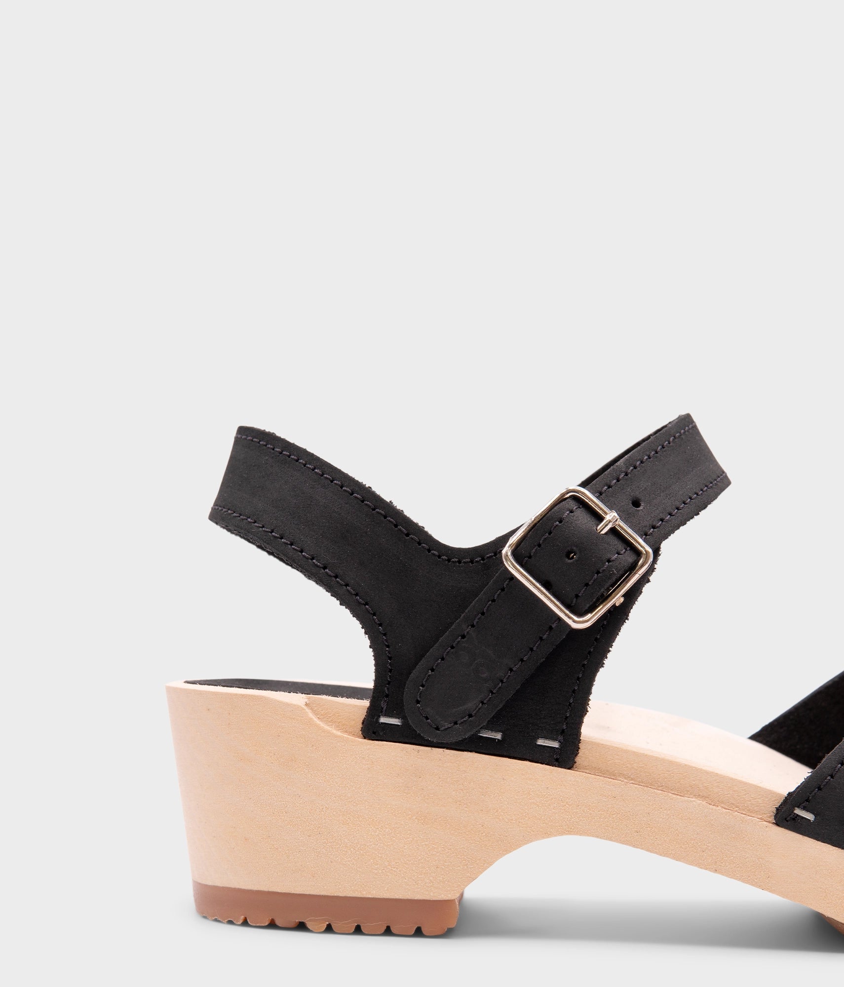 classic low heeled closed-toe sandal in black nubuck leather stapled on a light wooden base
