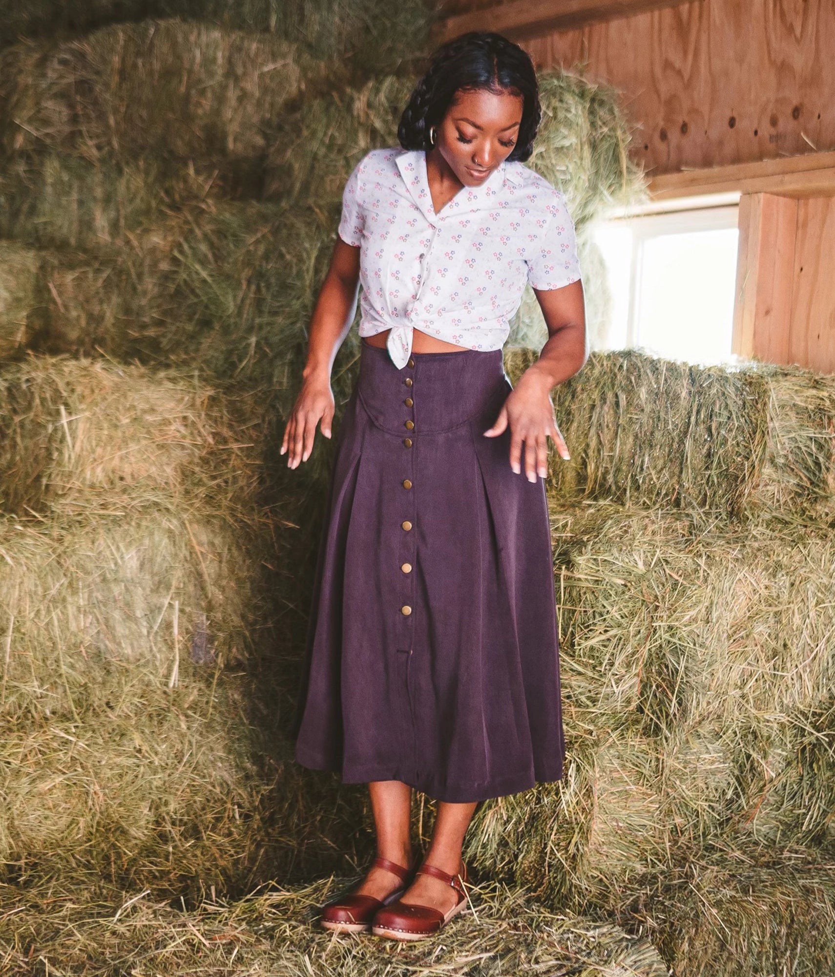 Woman wearing classic low heeled closed-toe sandal in cognac red vegetable tanned leather stapled on a light wooden base