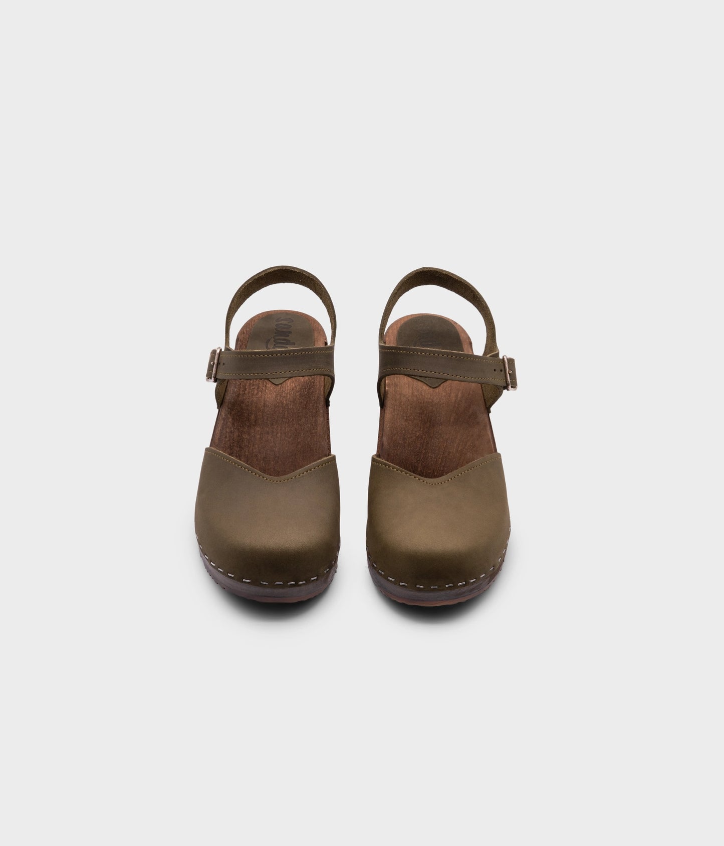 classic low heeled closed-toe sandal in olive green nubuck leather stapled on a dark wooden base