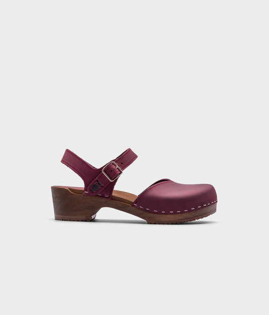 classic low heeled closed-toe sandal in purple plum nubuck leather stapled on a dark wooden base