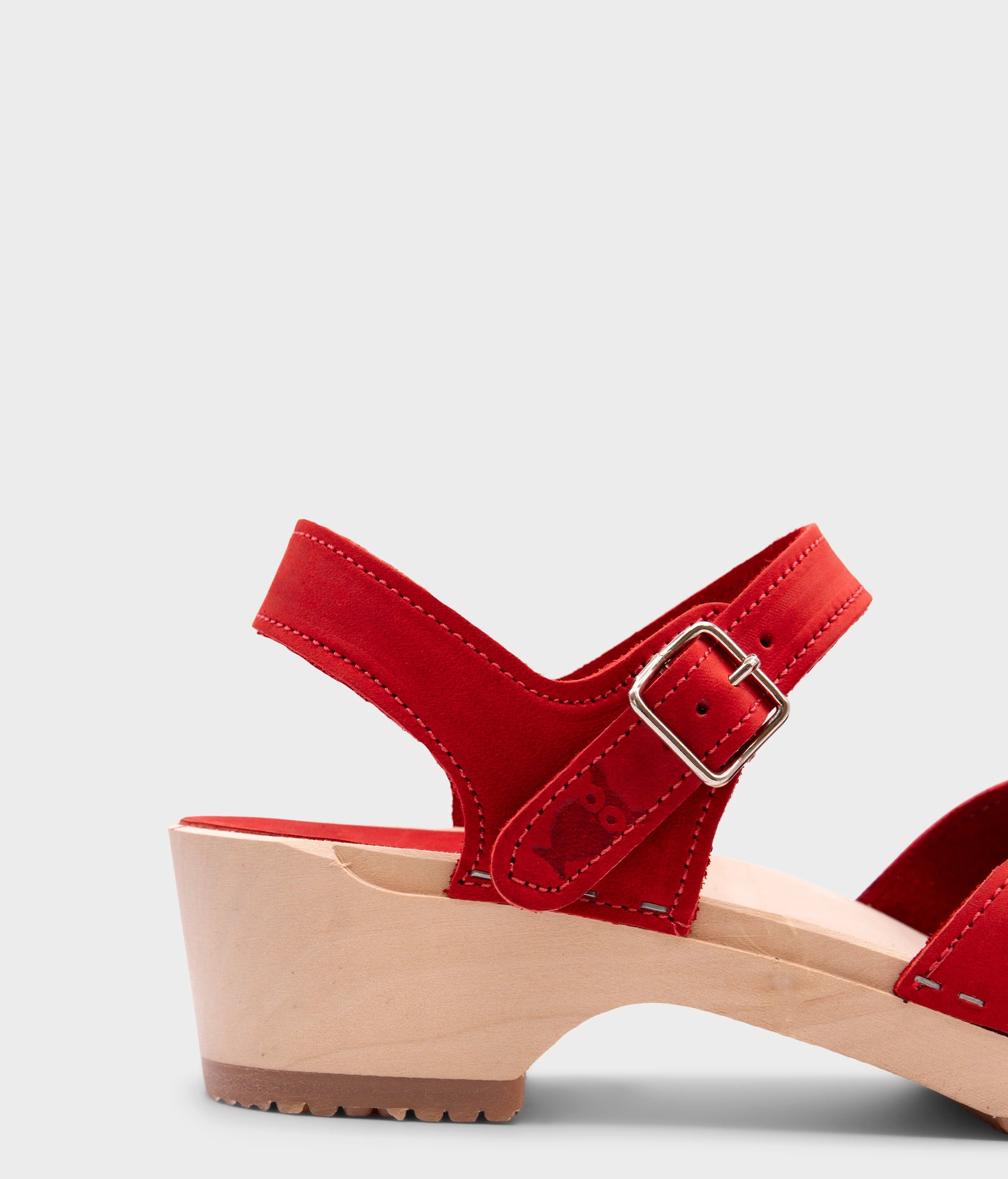 classic low heeled closed-toe sandal in red nubuck leather stapled on a light wooden base