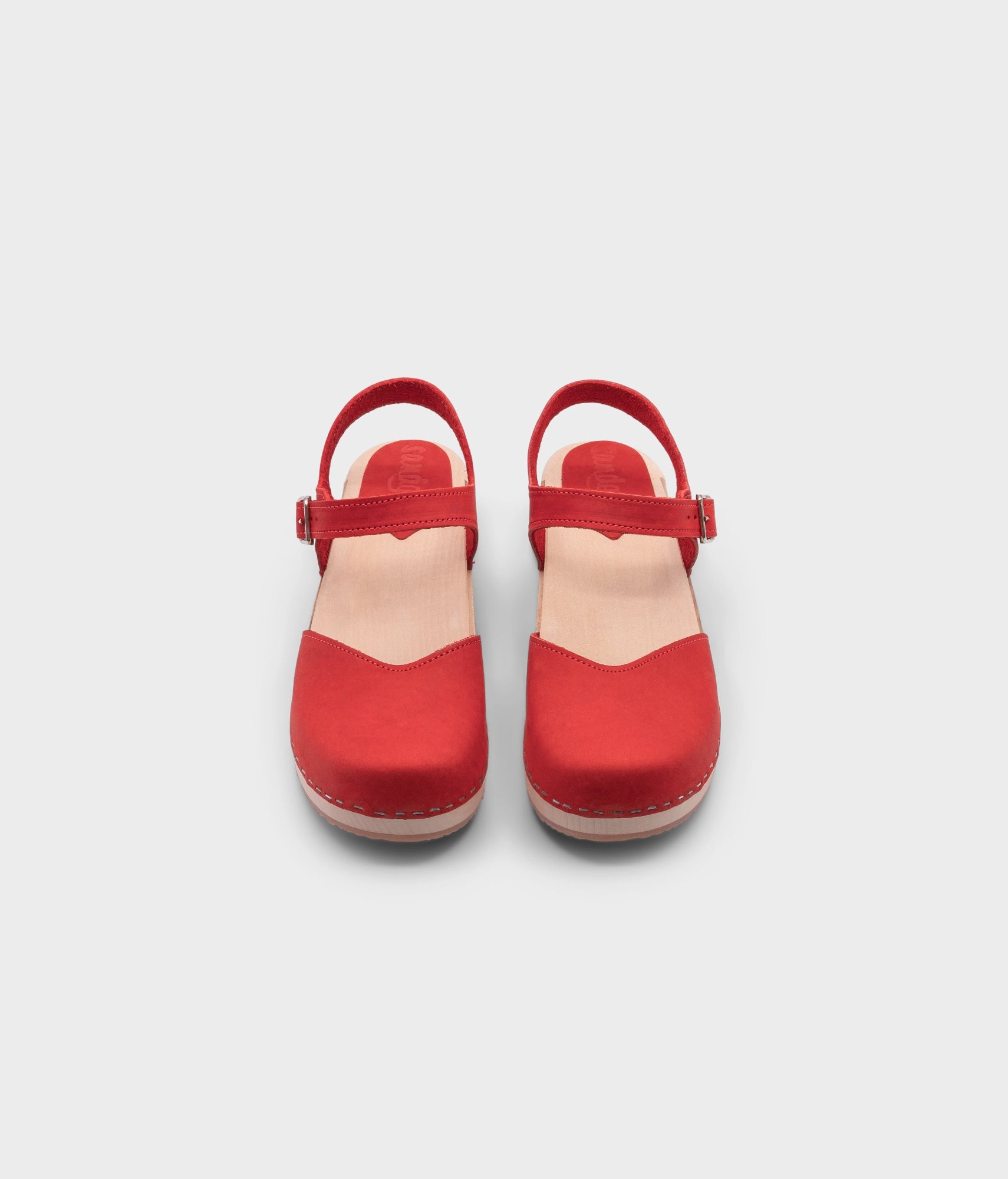 classic low heeled closed-toe sandal in red nubuck leather stapled on a light wooden base