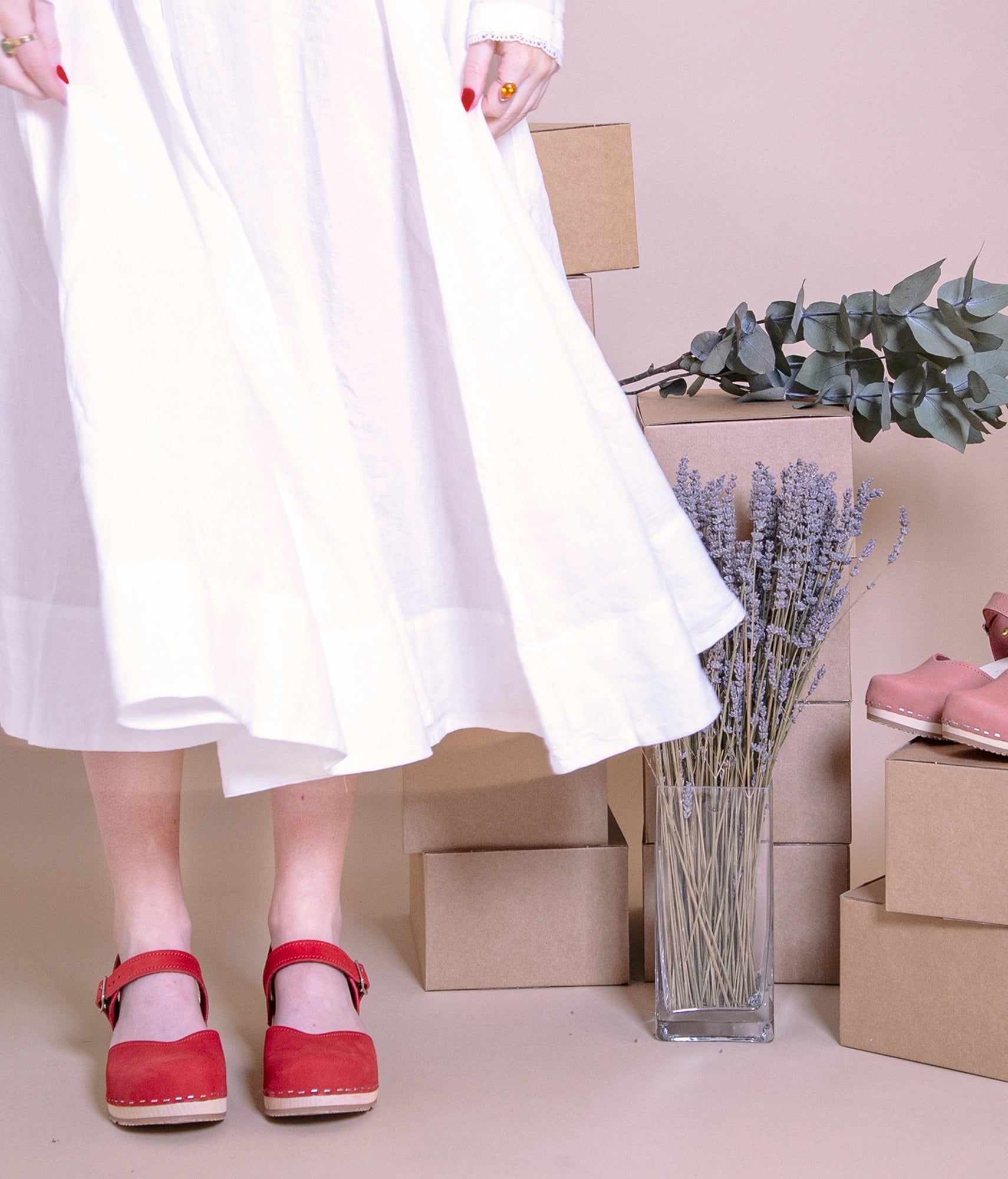 classic low heeled closed-toe sandal in red nubuck leather stapled on a light wooden base