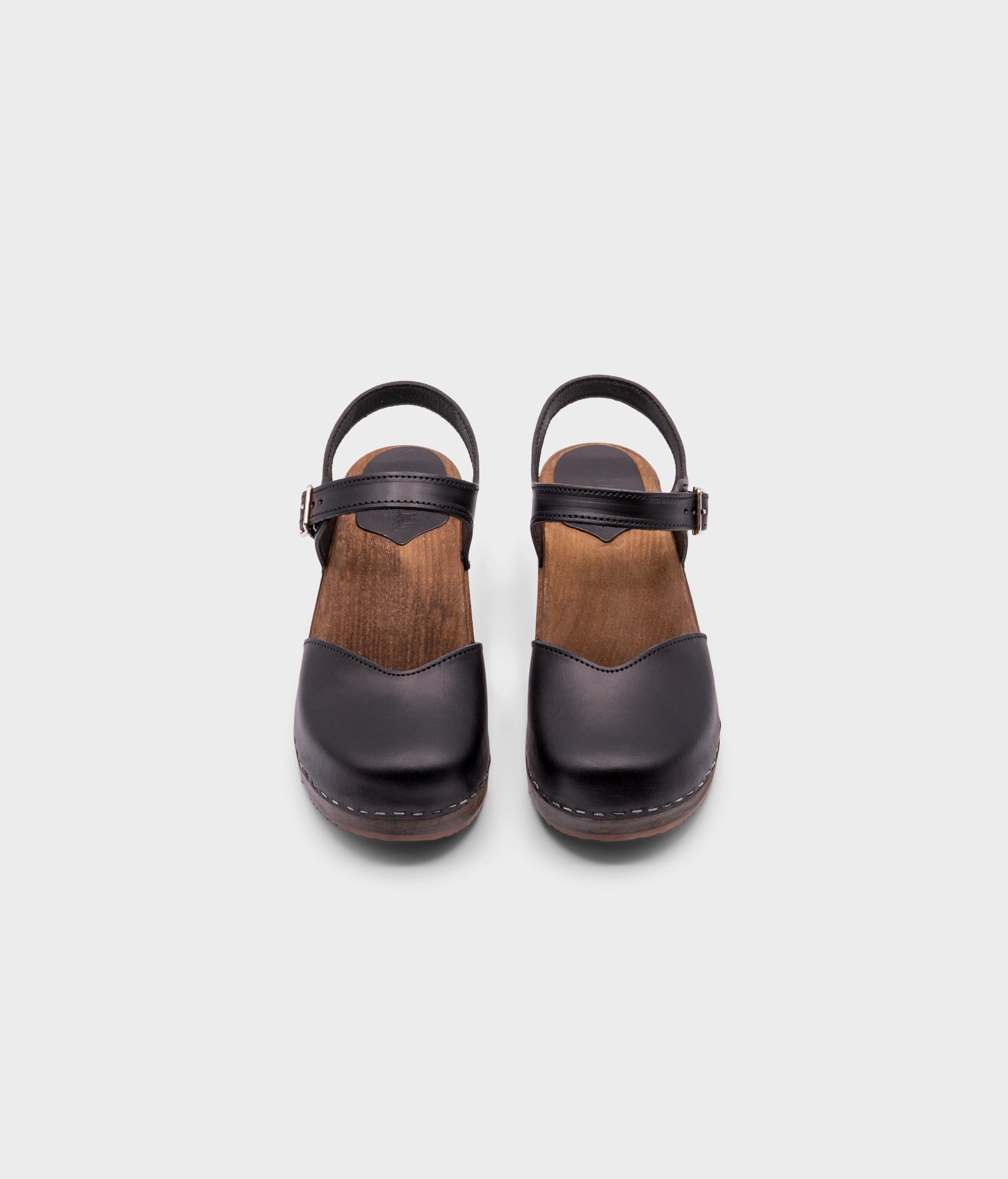 classic low heeled closed-toe sandal in black vegetable tanned leather stapled on a dark wooden base
