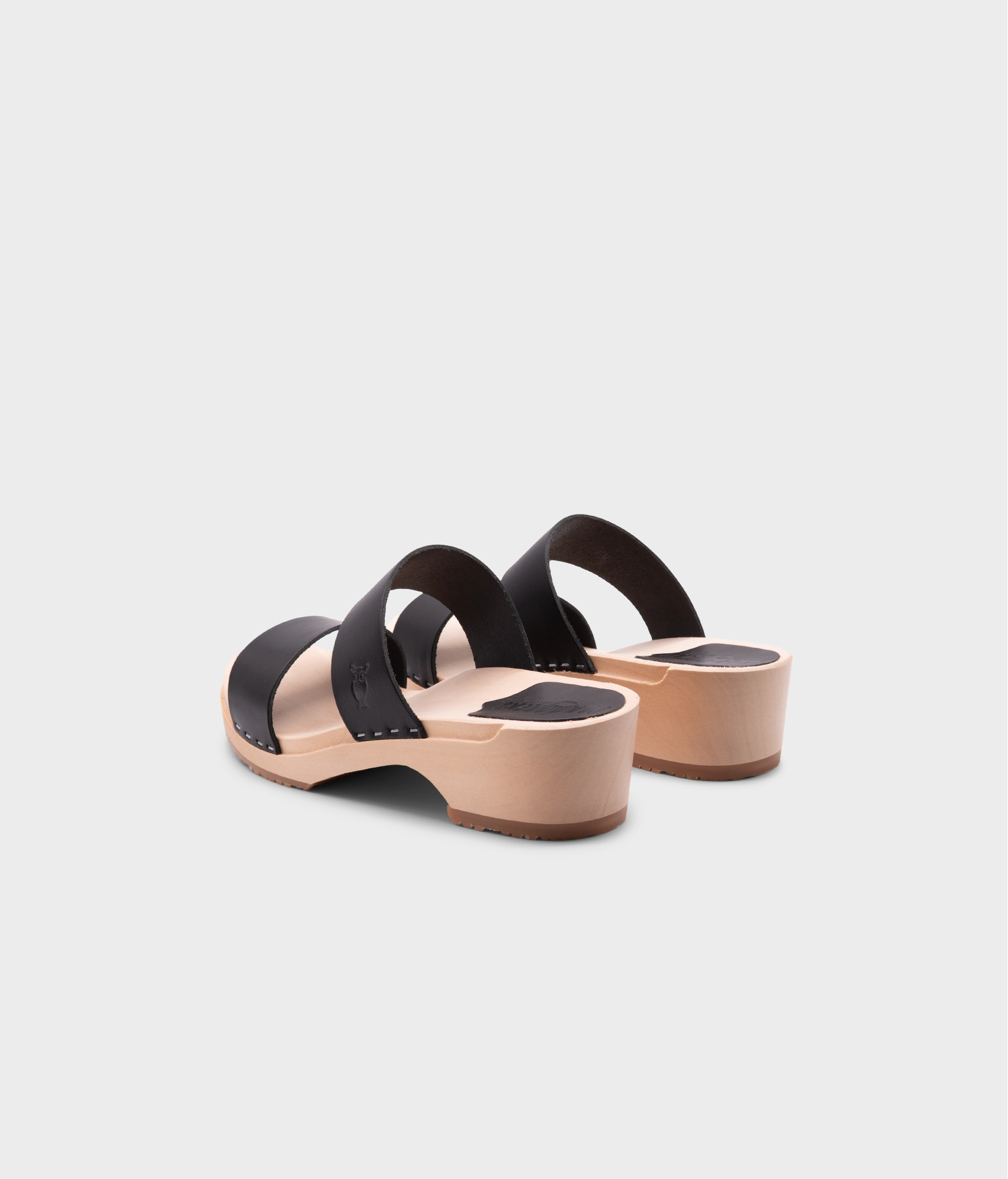 low heeled slip-in clog sandal with open toe in black vegetable tanned leather stapled on a light wooden base