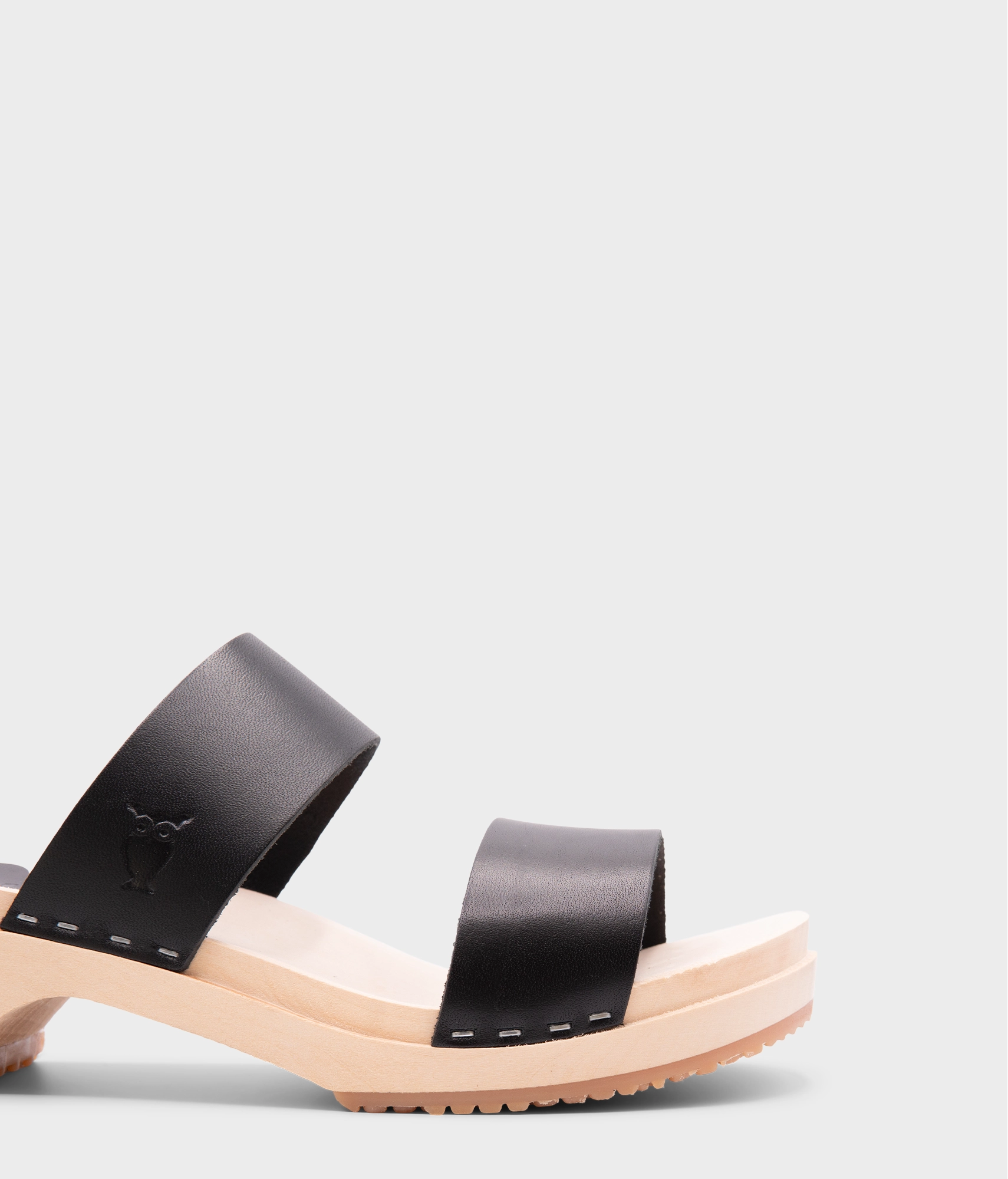 low heeled slip-in clog sandal with open toe in black vegetable tanned leather stapled on a light wooden base