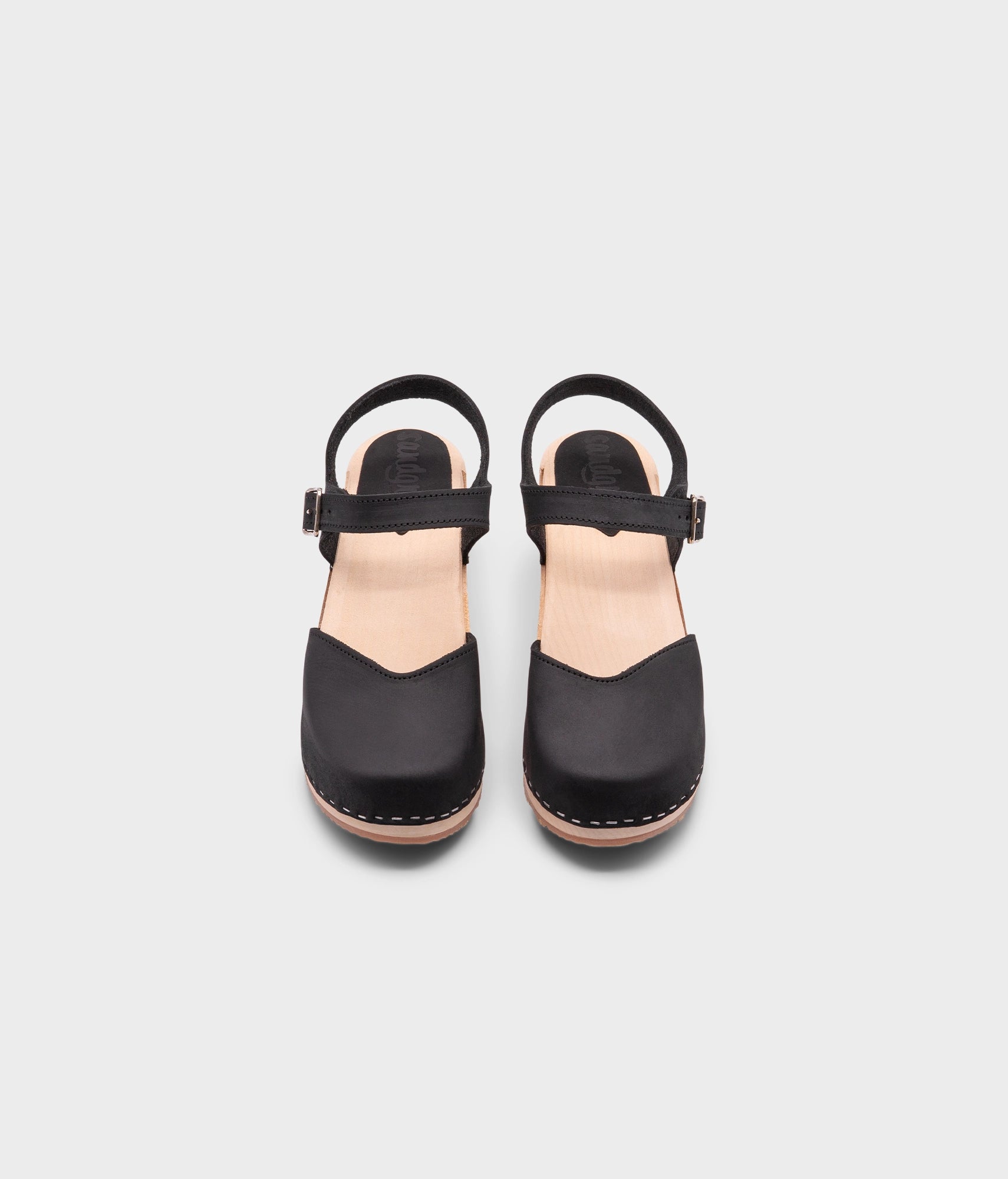 high heeled closed-toe clog sandal in black nubuck leather stapled on a light wooden base