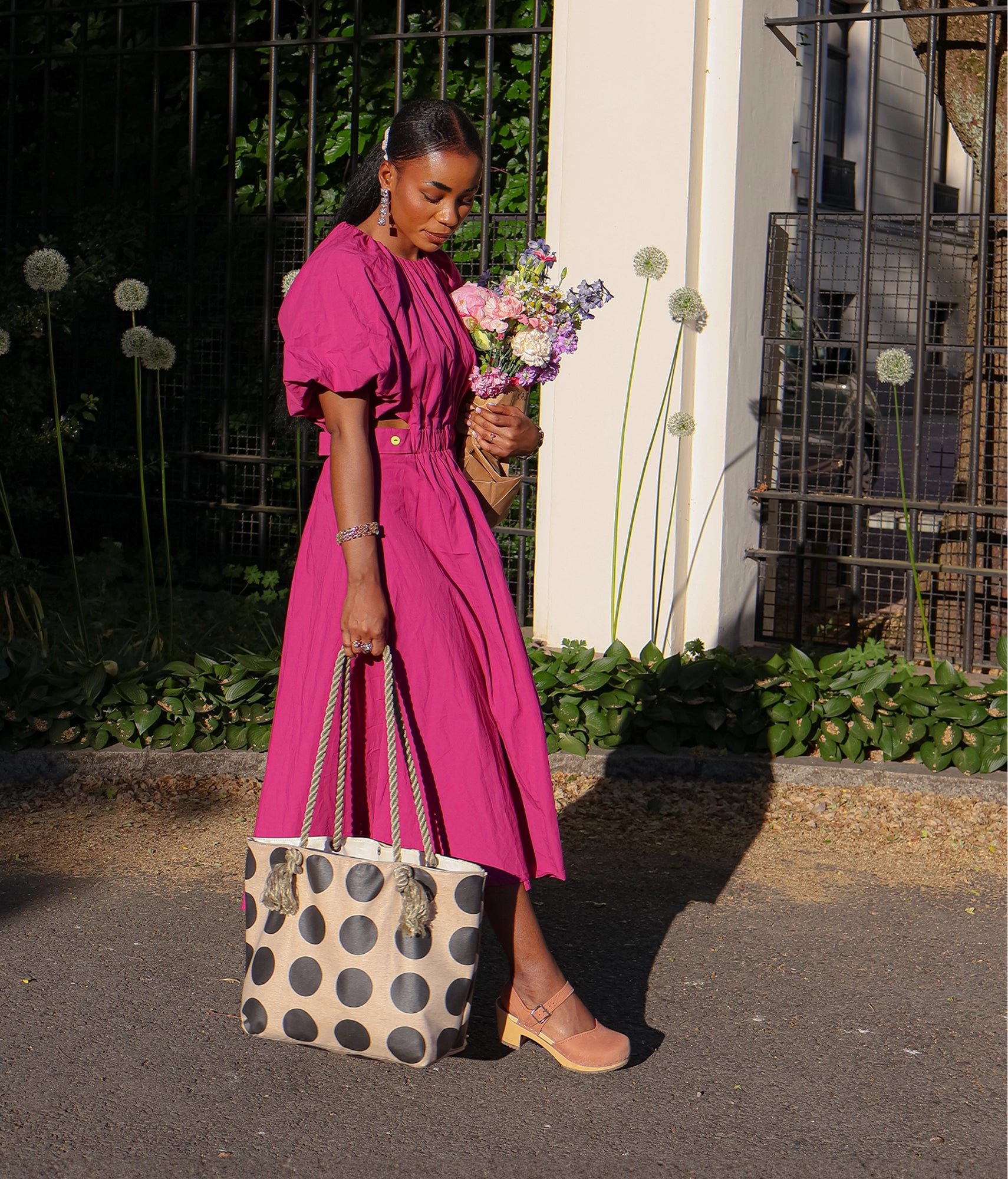 woman wearing a pink dress and a pair of high heeled closed-toe clog sandal in blush pink nubuck leather stapled on a light wooden base