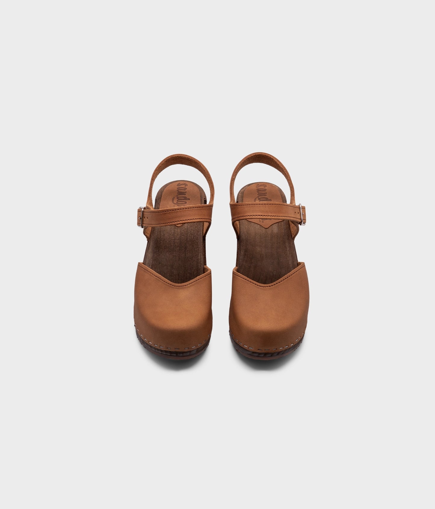 high heeled closed-toe clog sandal in light brown nubuck leather stapled on a dark wooden base