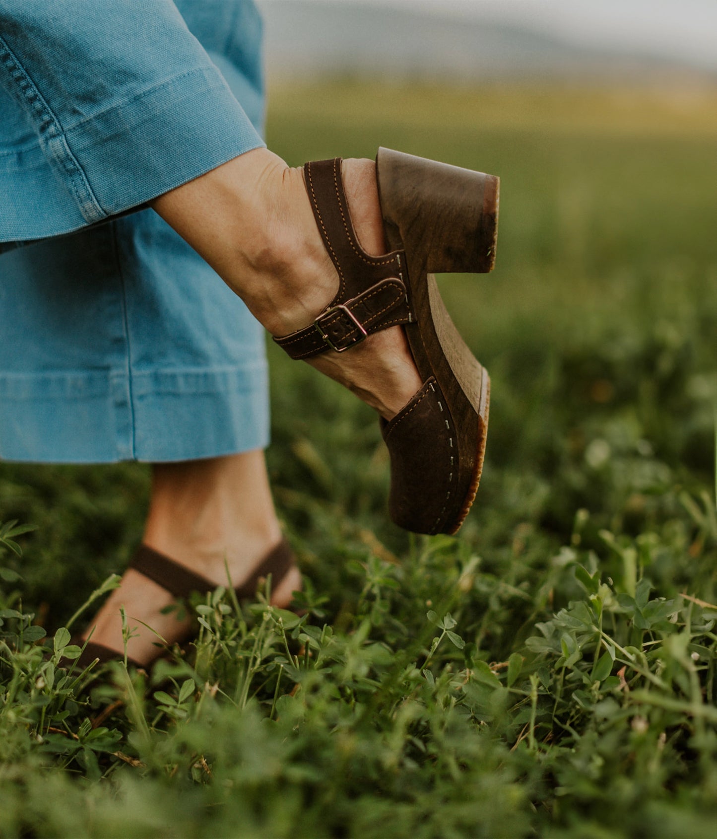 high heeled closed-toe clog sandal in dark brown nubuck leather stapled on a dark wooden base