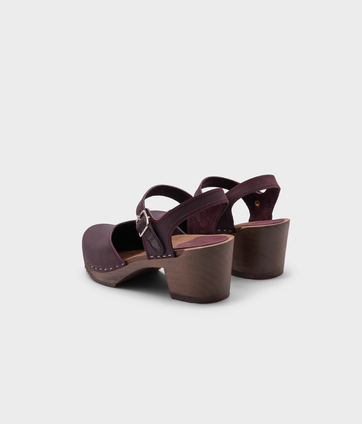 high heeled closed-toe clog sandal in purple plum nubuck leather stapled on a dark wooden base