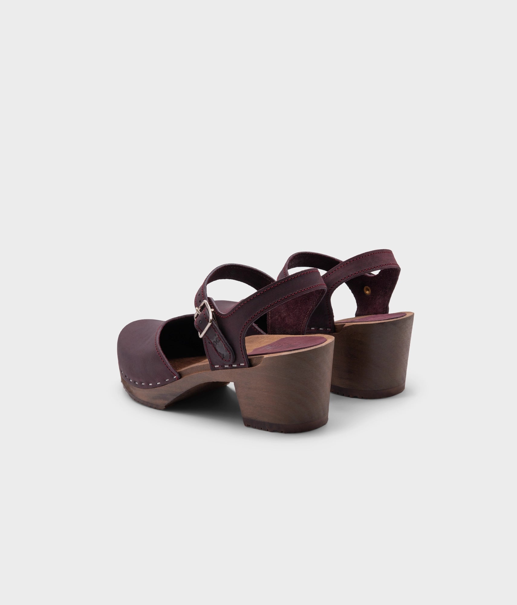 high heeled closed-toe clog sandal in purple plum nubuck leather stapled on a dark wooden base