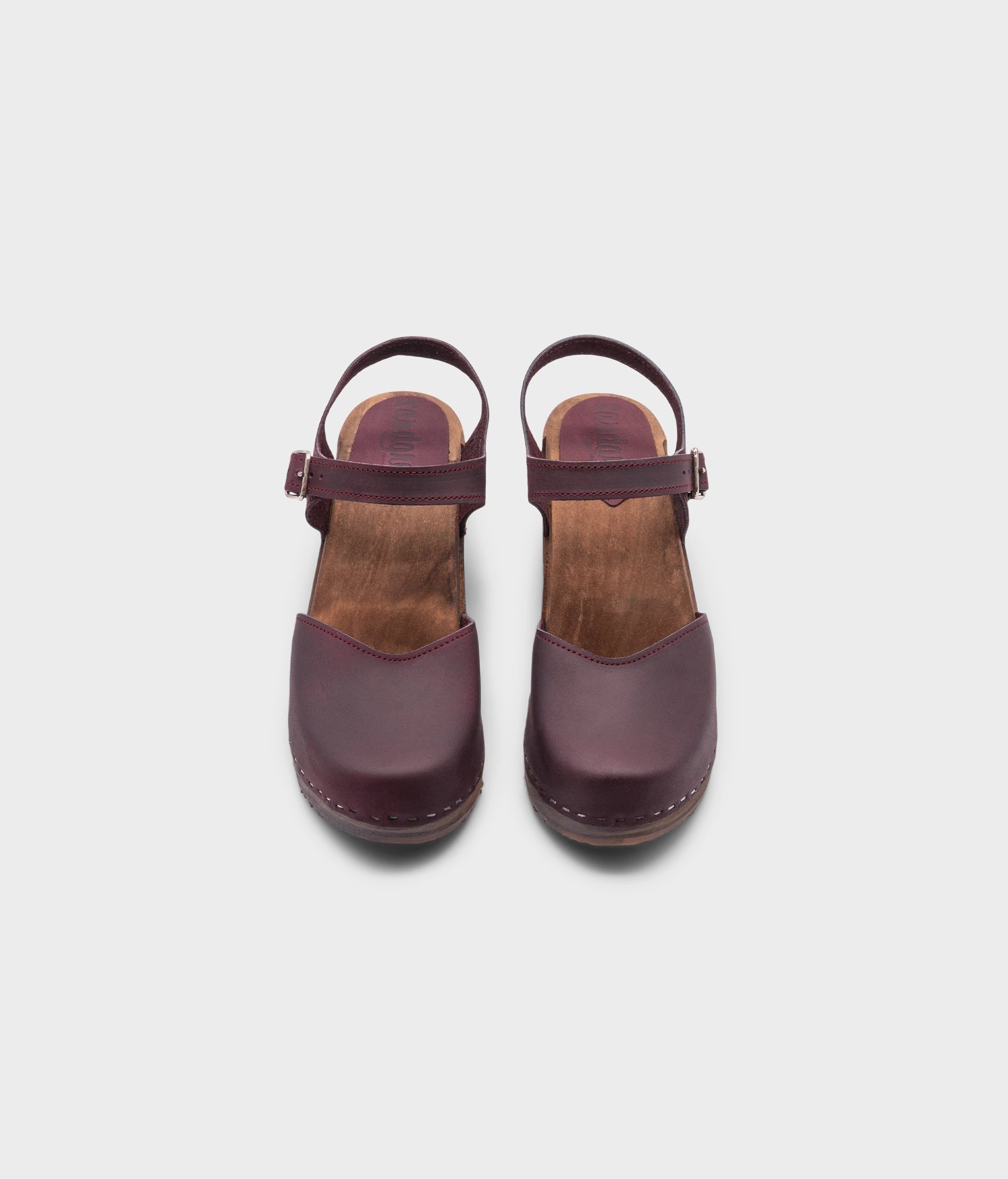 high heeled closed-toe clog sandal in purple plum nubuck leather stapled on a dark wooden base