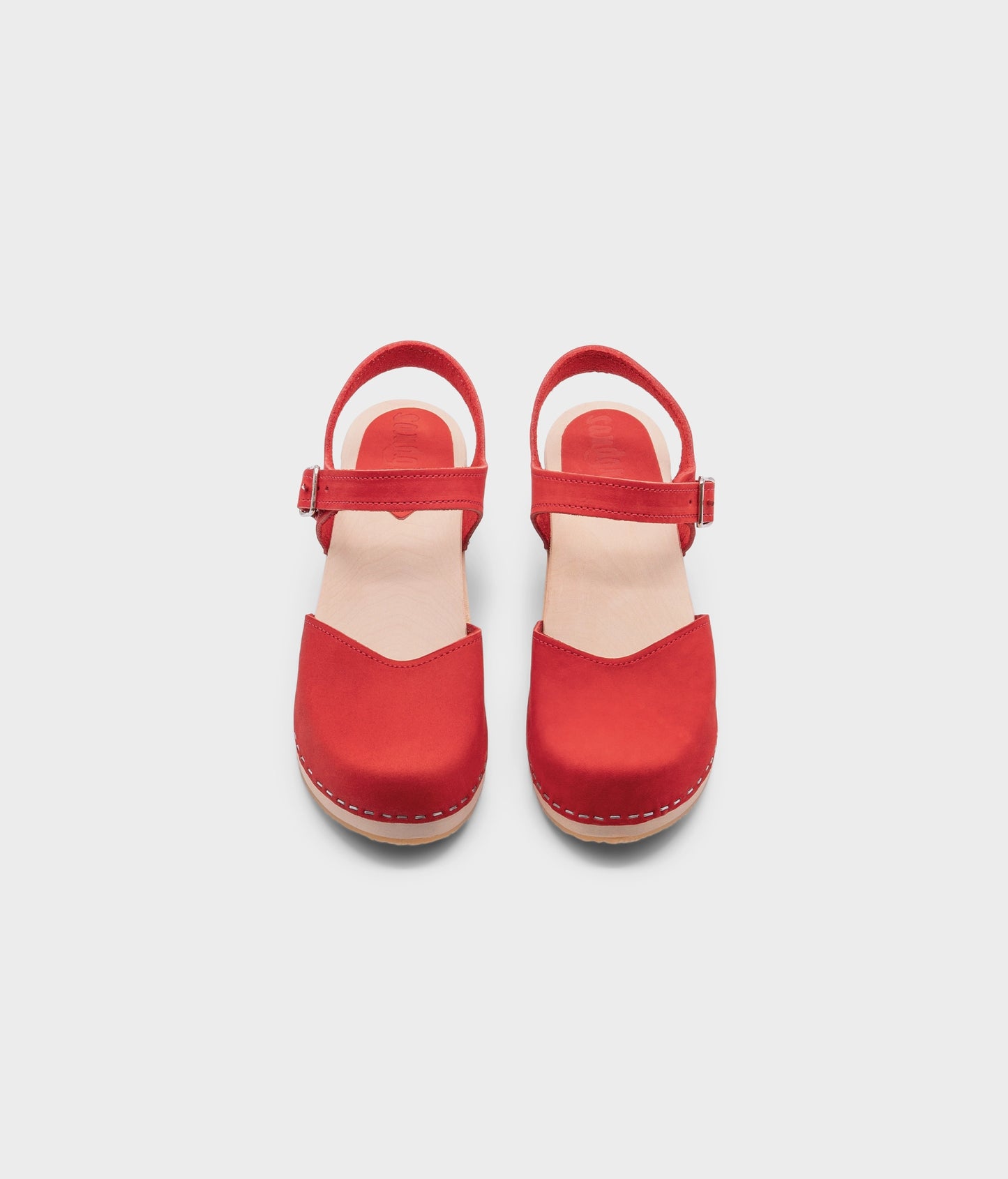 high heeled closed-toe clog sandal in red nubuck leather stapled on a light wooden base
