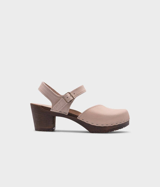 high heeled closed-toe clog sandal in sand white nubuck leather stapled on a dark wooden base