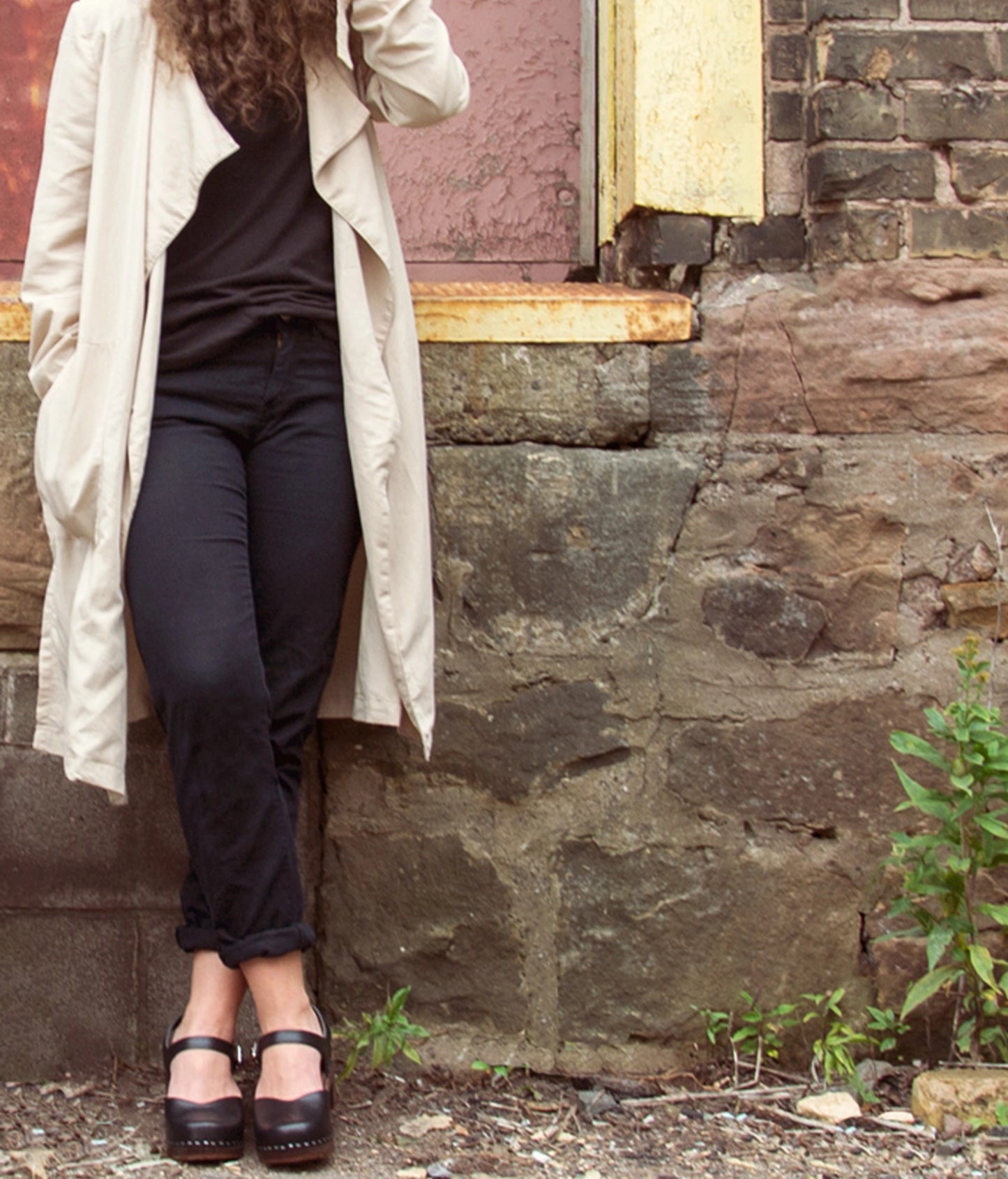Women wearing high heeled closed-toe clog sandal in black vegetable tanned leather stapled on a dark wooden base