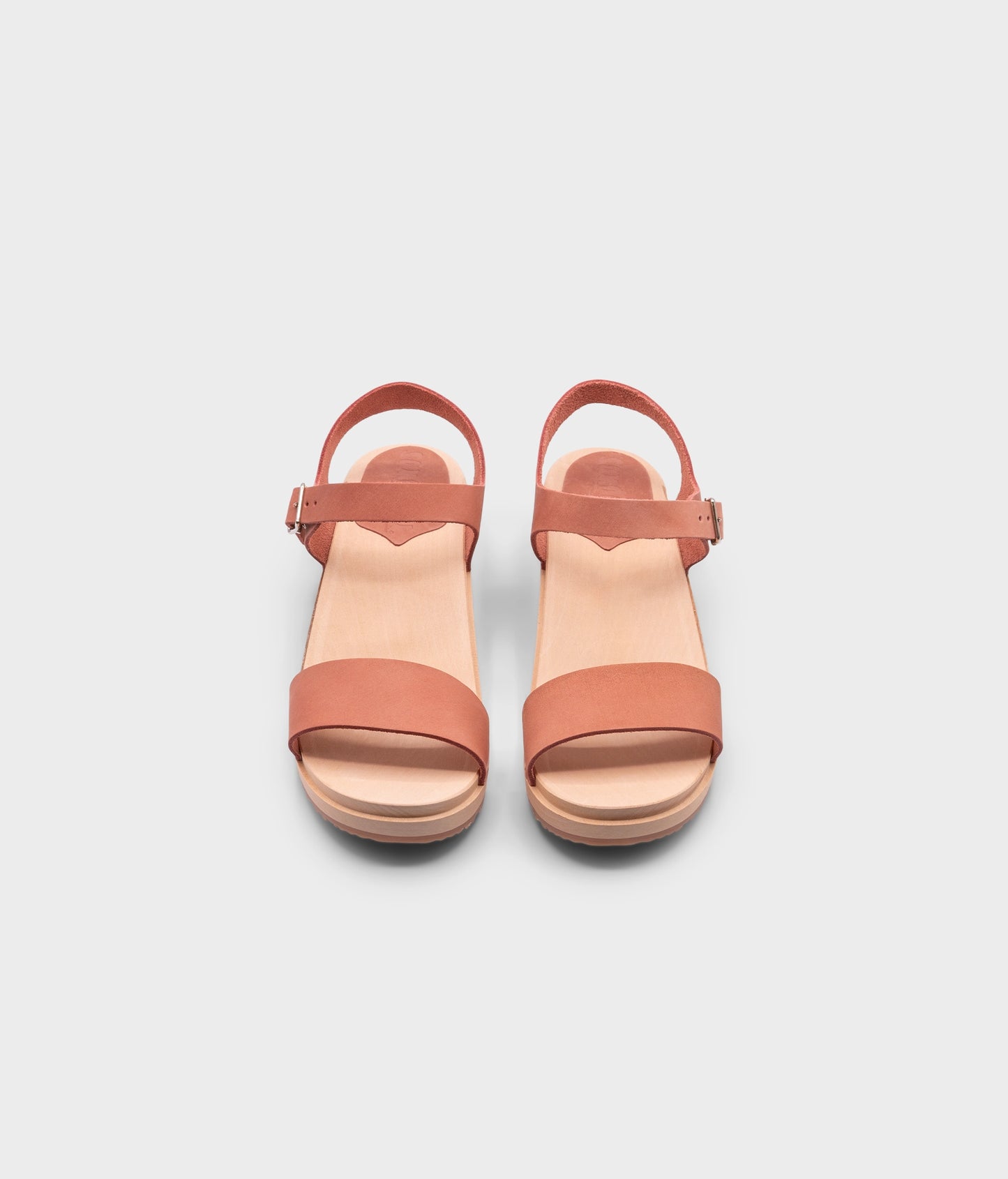 low heeled open-toe clog sandal in blush pink nubuck leather stapled on a light wooden base