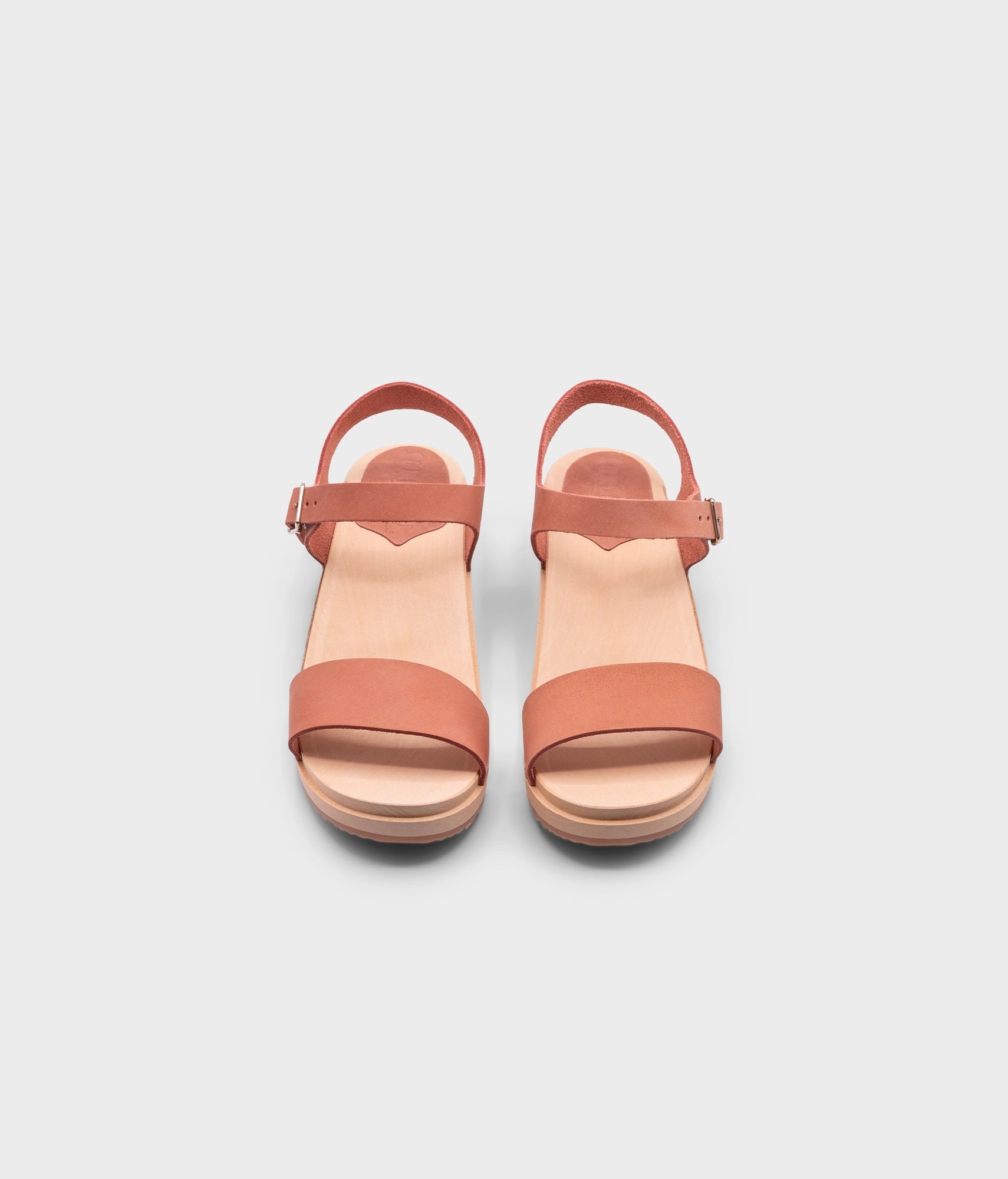 low heeled open-toe clog sandal in blush pink nubuck leather stapled on a light wooden base
