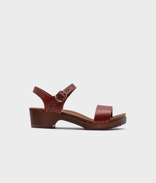 low heeled open-toe clog sandal in cognac red vegetable tanned leather stapled on a dark wooden base