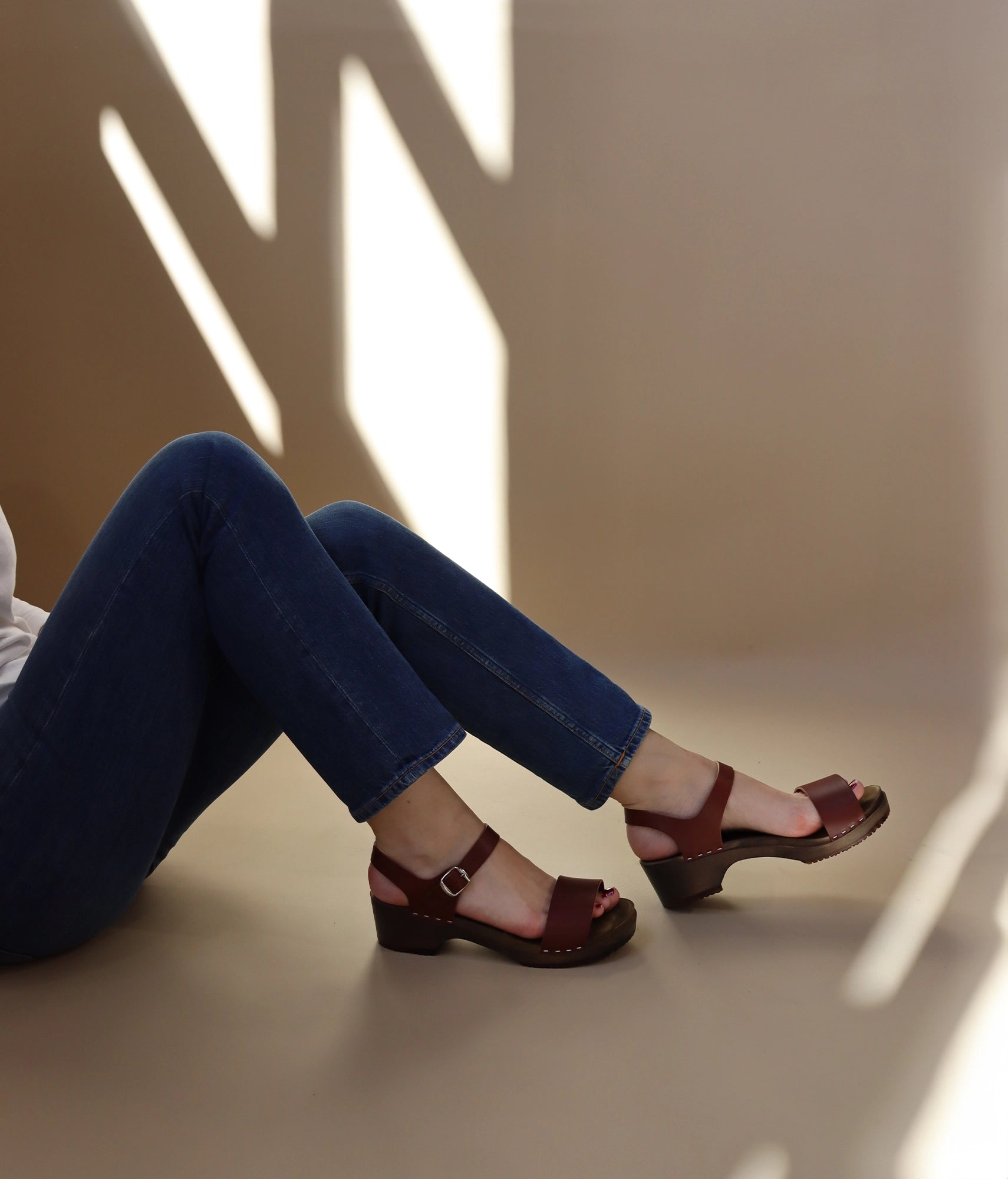 low heeled open-toe clog sandal in cognac red vegetable tanned leather stapled on a dark wooden base
