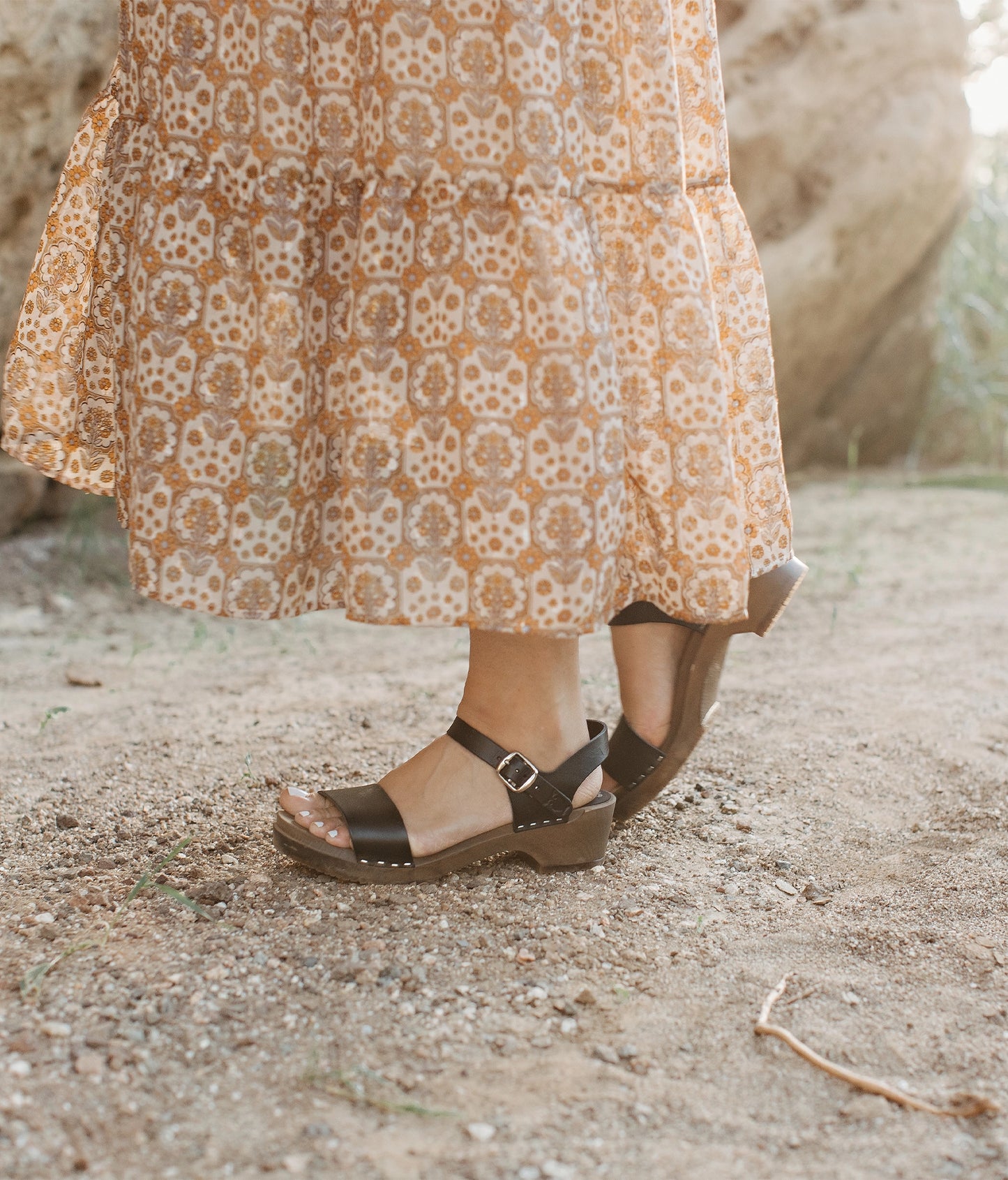 low heeled open-toe clog sandal in black vegetable tanned leather stapled on a dark wooden base